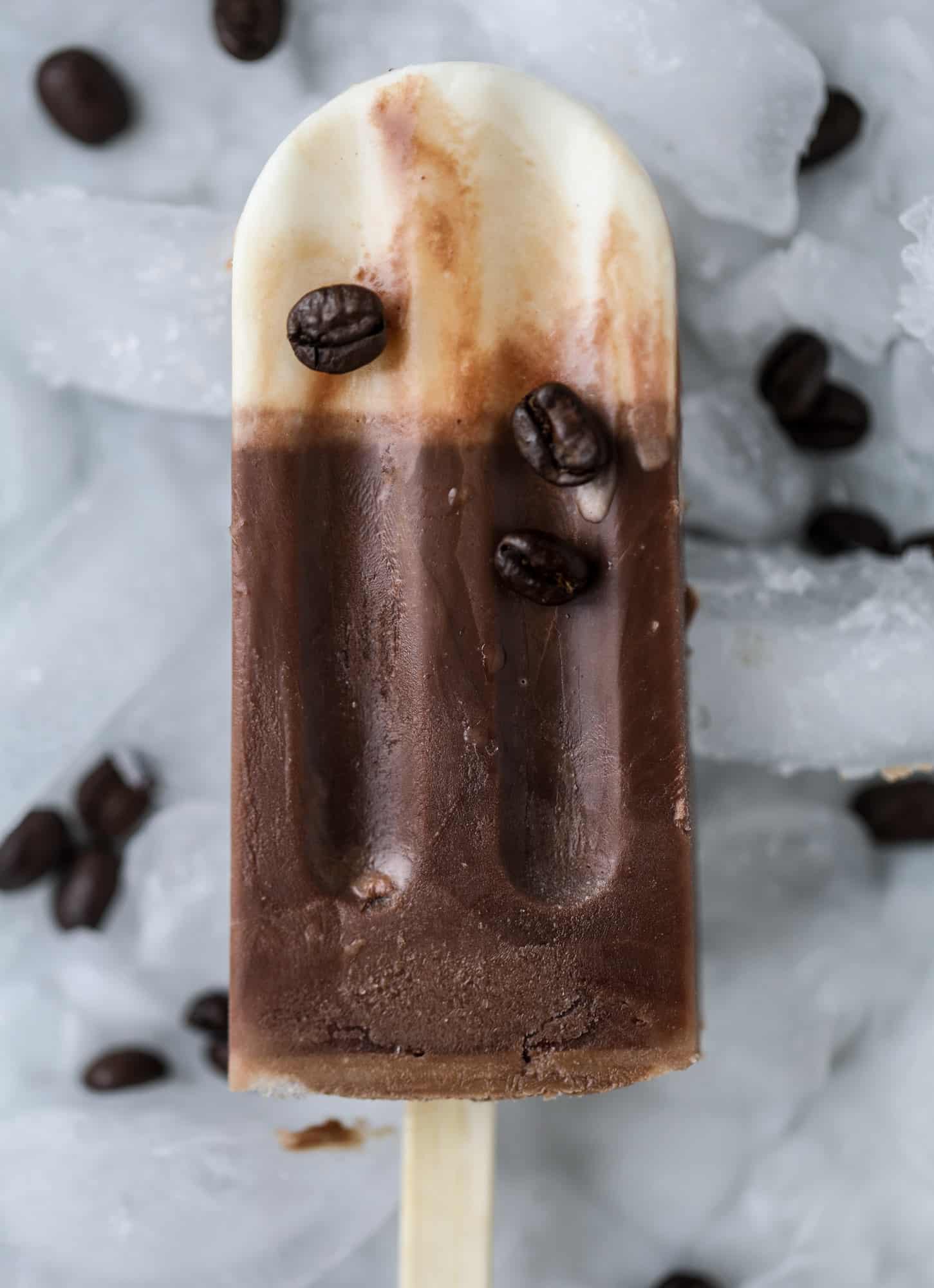 These fudgesicles are made with cold brew and dutch process cocoa for the most fun grown-up popsicle that can also deliver a little caffeine jolt. Topped with vanilla bean sweet cream, these are just like an iced latte in a pop! Serve as a treat or a snack! I howsweeteats.com #coldbrew #coffee #sweet #cream #popsicle #fudgesicle