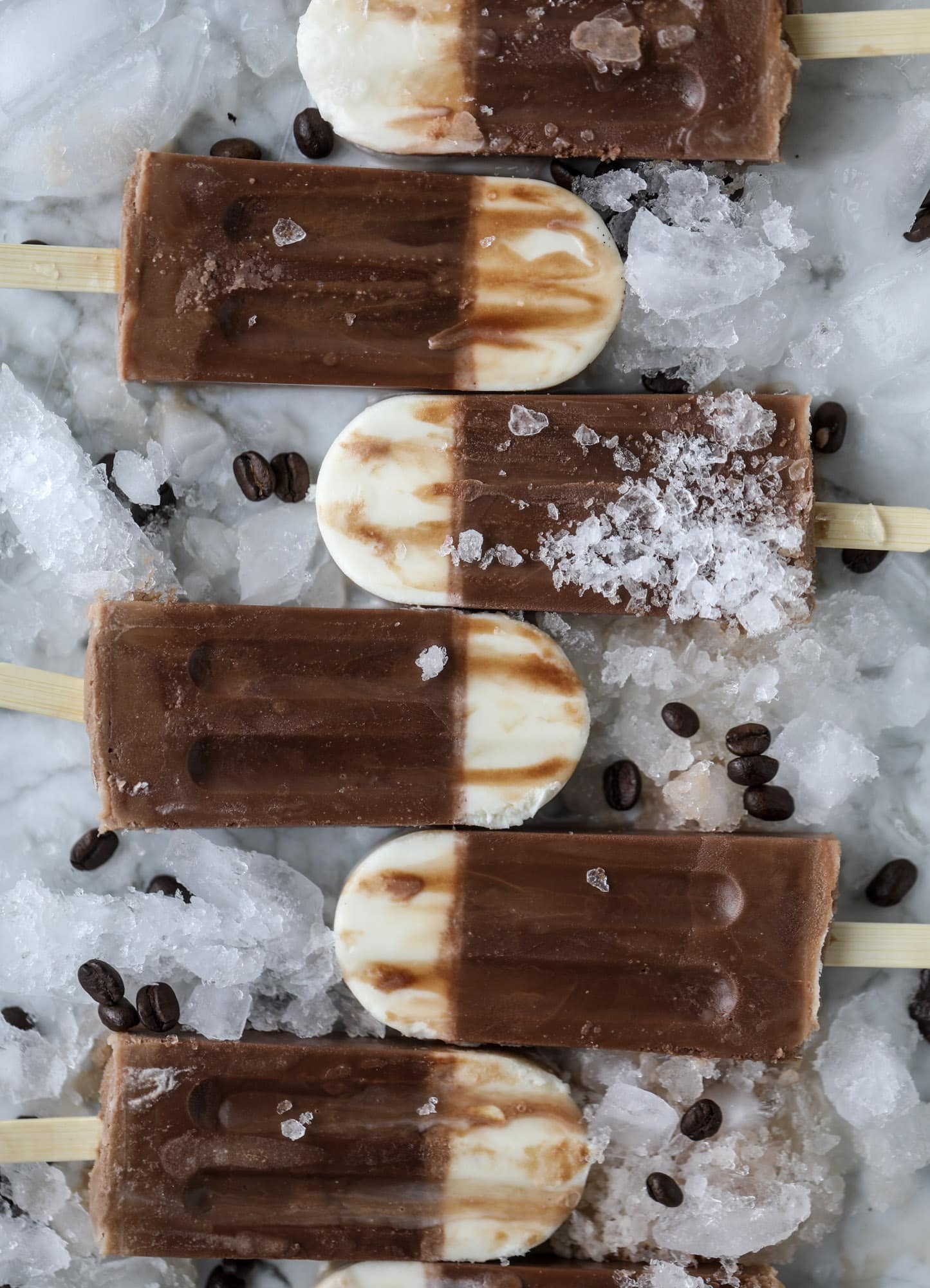 These fudgesicles are made with cold brew and dutch process cocoa for the most fun grown-up popsicle that can also deliver a little caffeine jolt. Topped with vanilla bean sweet cream, these are just like an iced latte in a pop! Serve as a treat or a snack! I howsweeteats.com #coldbrew #coffee #sweet #cream #popsicle #fudgesicle