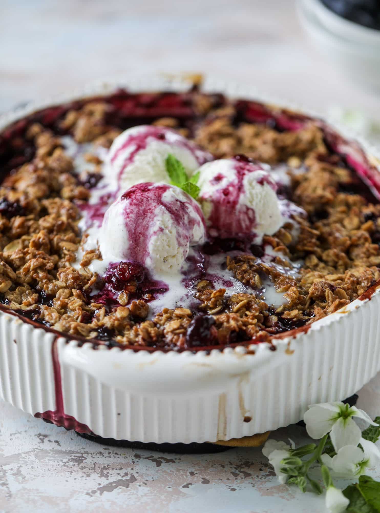 This blueberry crisp is warm and bursting with sweet and juicy fruit. It's topped with a quinoa oatmeal brown sugar topping and is the perfect dessert for summer. Served warm and topped with vanilla ice cream, it's just divine! I howsweeteats.com #blueberry #crisp #quinoa #oats #dessert #fruit