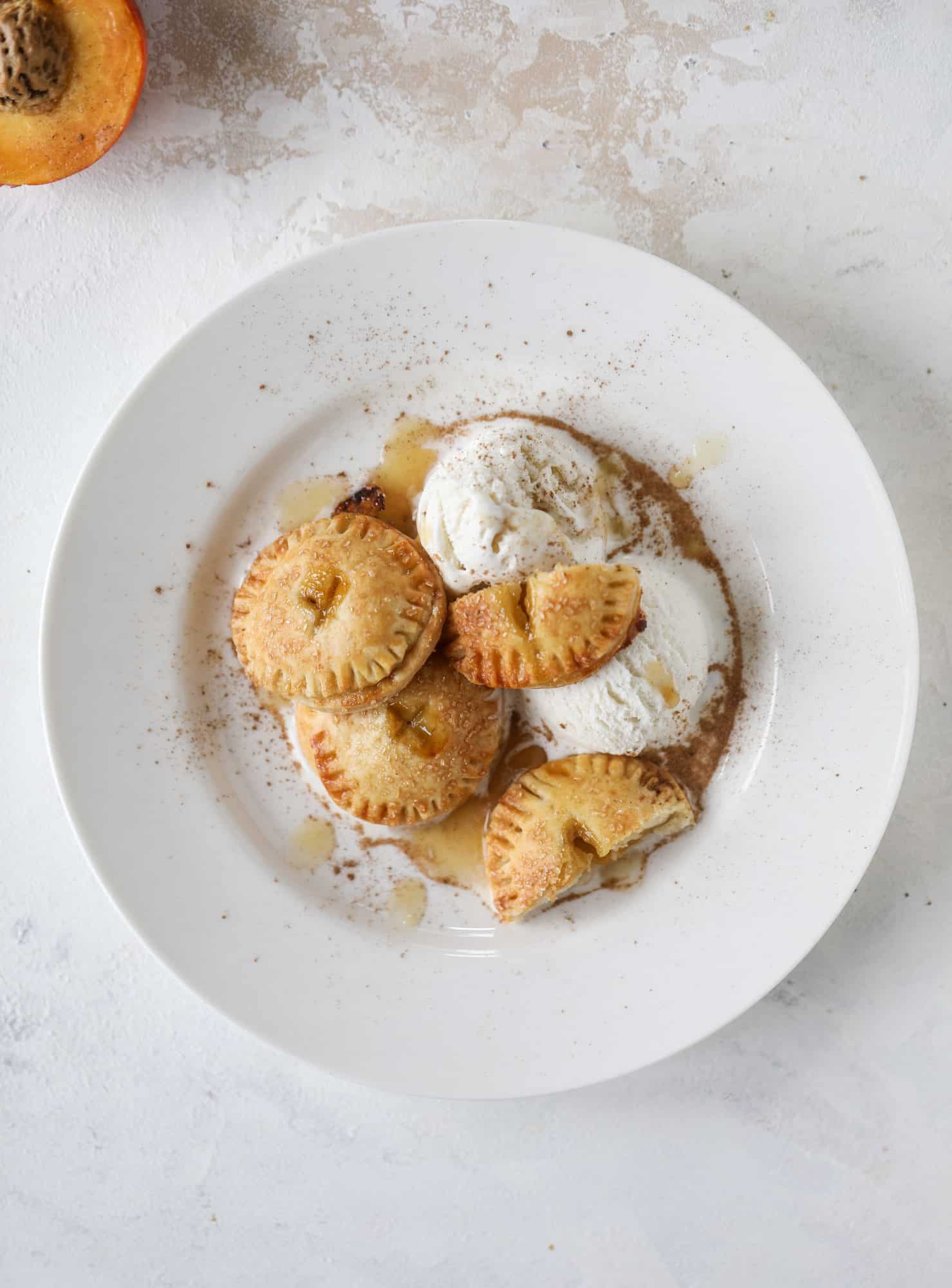 These little peach hand pies are super easy to make and oh-so delicious for summer! A warm and syrupy homemade peach filling made with brown sugar and bourbon, stuck inside a flakey all-butter crust and sprinkled with coarse sugar. SO GOOD. I howsweeteats.com #peach #hand #pies #mini #dessert #summer