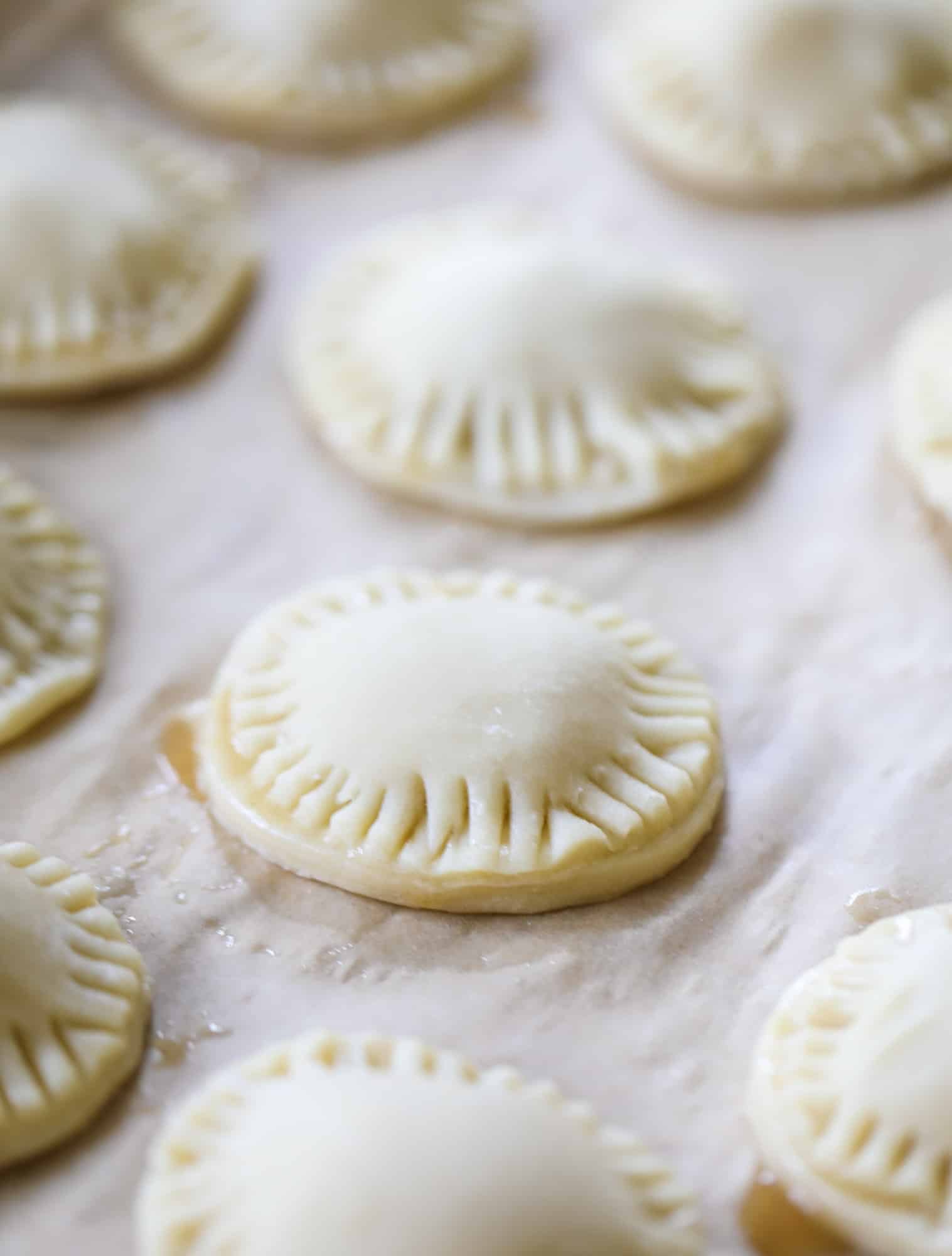 These little peach hand pies are super easy to make and oh-so delicious for summer! A warm and syrupy homemade peach filling made with brown sugar and bourbon, stuck inside a flakey all-butter crust and sprinkled with coarse sugar. SO GOOD. I howsweeteats.com #peach #hand #pies #mini #dessert #summer