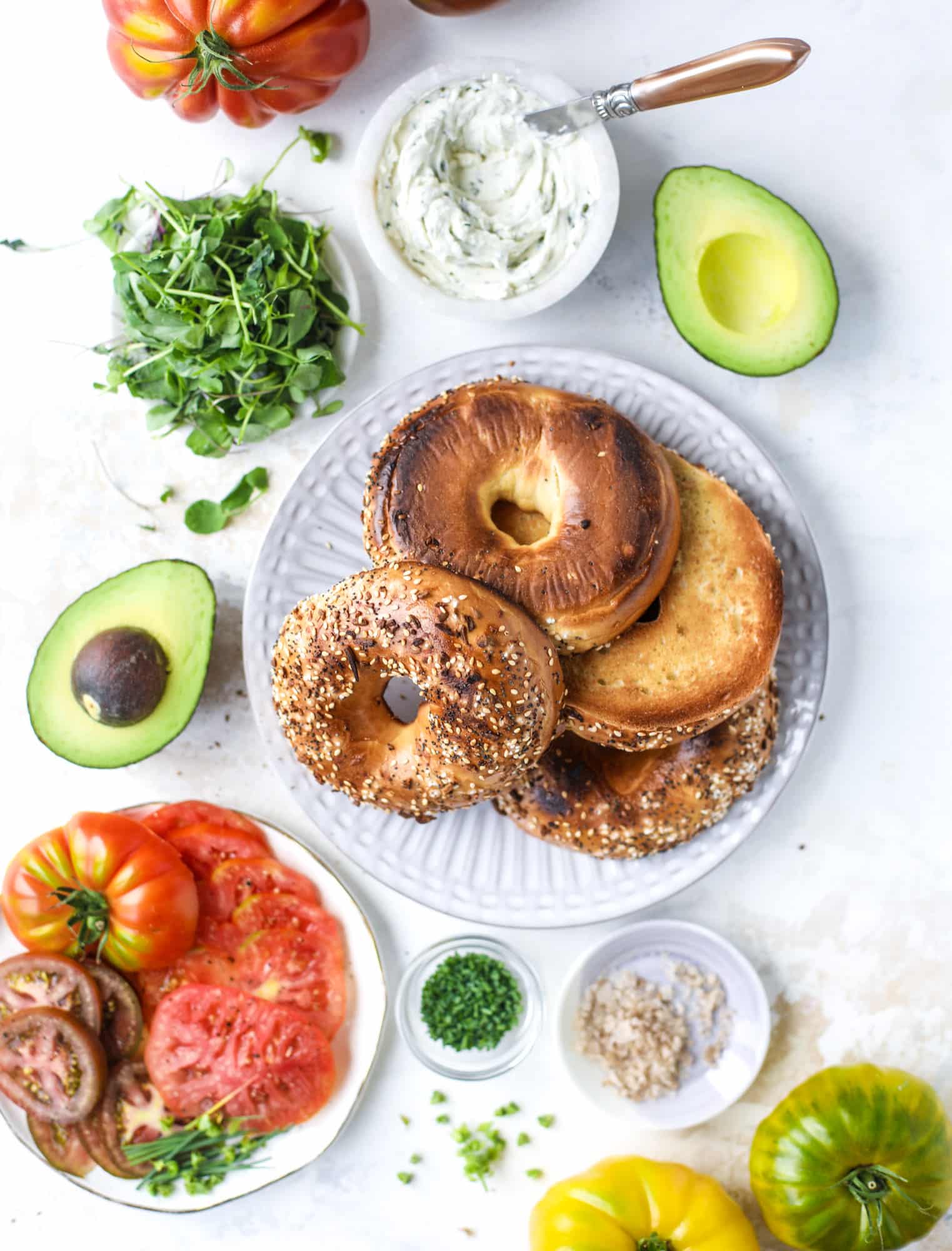 These avocado tomato sandwiches are the perfect lunch! Complete with veggie cream cheese, smoked sea salt, fresh chives and microgreens, the sliced avocado and heirloom tomatoes are sandwiched on an everything bagel for a flavor explosion. I howsweeteats.com #avocado #tomato #sandwich #healthy #lunch