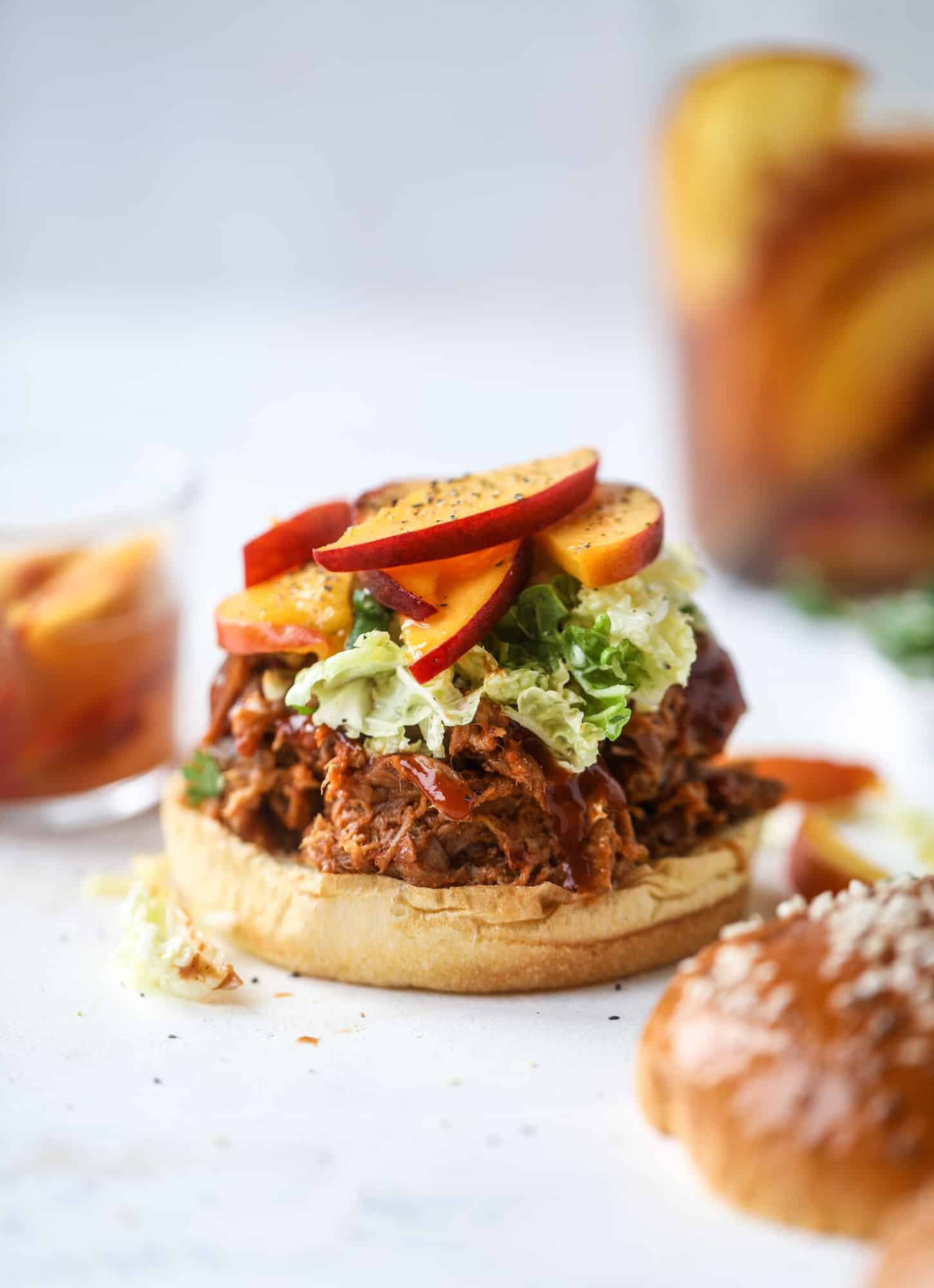 This chipotle pulled pork sandwich is spicy, sweet and saucy. Throw it on a bun or a plate and top it with the most delicious quick pickled peaches and napa cabbage slaw. Flavor and texture make this sandwich incredible! I howsweeteats.com #pulled #pork #chipotle #pickled #peaches #slaw #sandwiches #slow #cooker