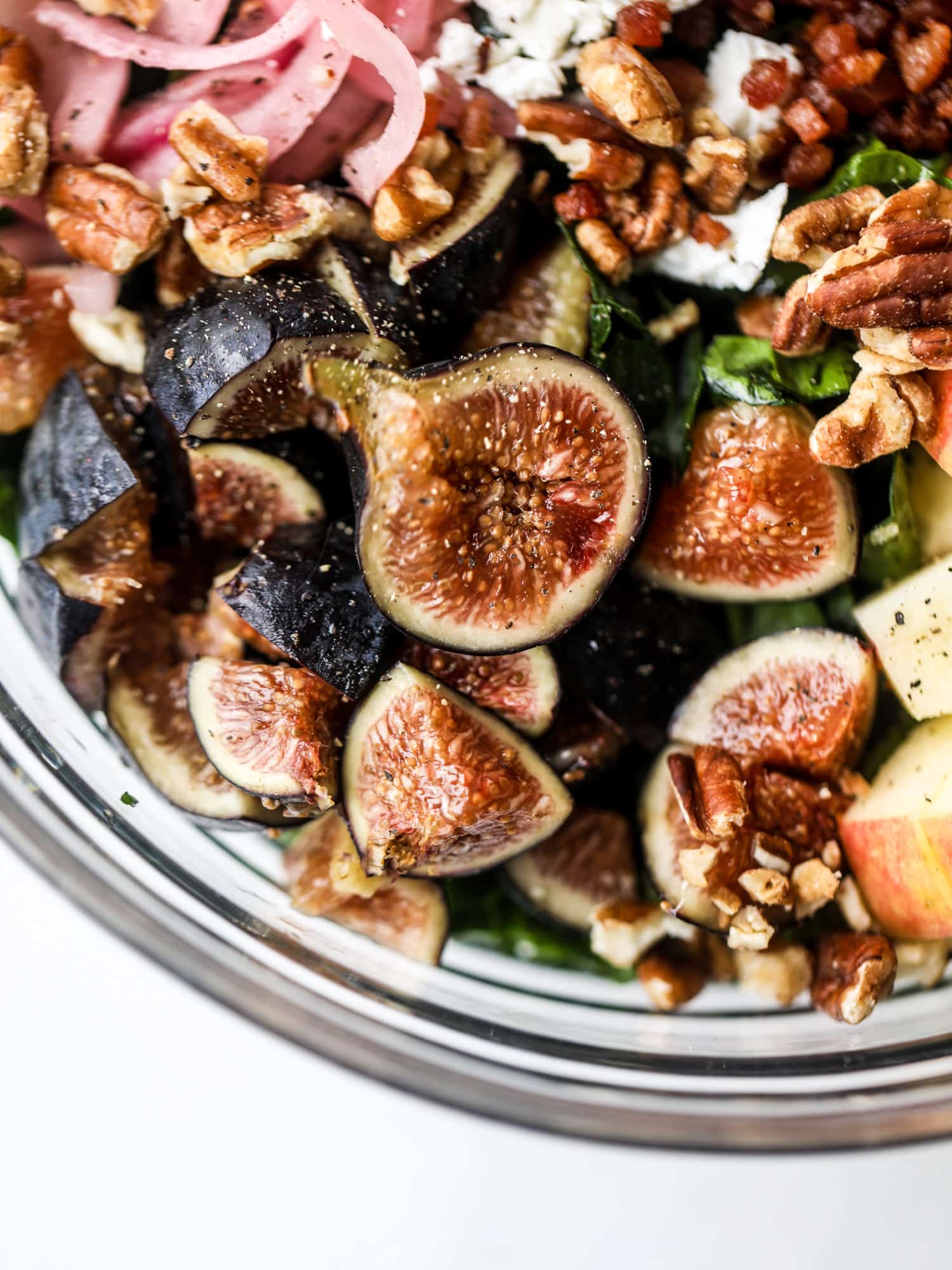 This fall kale salad is perfect for the season and full of so much delicious flavor! Shredded kale, honeycrisp apple, fresh figs, pancetta, pickled onions, pecans and goat cheese come together with a maple cider vinaigrette for salad heaven. I howsweeteats.com #fall #kale #salad #apples #figs #pecans