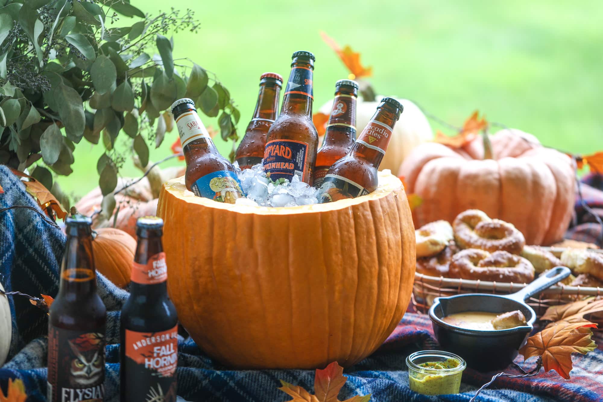 This is the cutest way ever to serve the best pumpkin beer! If you do a pumpkin beer party of a pumpkin beer tasting, this pumpkin cooler is an adorable (and easy!) way to make things festive. Kick it up with a hot pretzel bar and lots of dipping sauce too! I howsweeteats.com #pumpkin #beer #cooler #softpretzel #fall #cheese