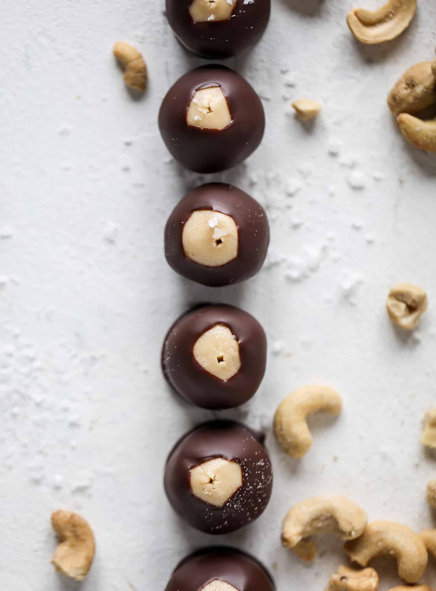 These cashew butter buckeyes are a fun and modern twist on the traditional buckeye recipe! Creamy cashew butter makes a delicious, rich dough and then it's coated in chocolate and sprinkled with sea salt. Delicious! I howsweeteats.com #cashewbutter #buckeyes