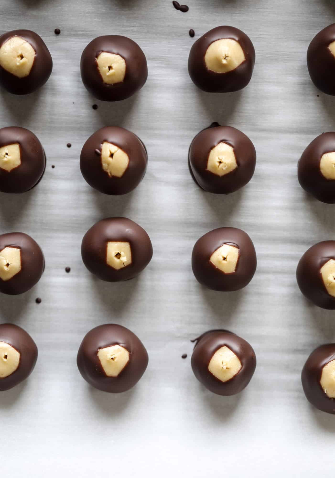 These cashew butter buckeyes are a fun and modern twist on the traditional buckeye recipe! Creamy cashew butter makes a delicious, rich dough and then it's coated in chocolate and sprinkled with sea salt. Delicious! I howsweeteats.com #cashewbutter #buckeyes