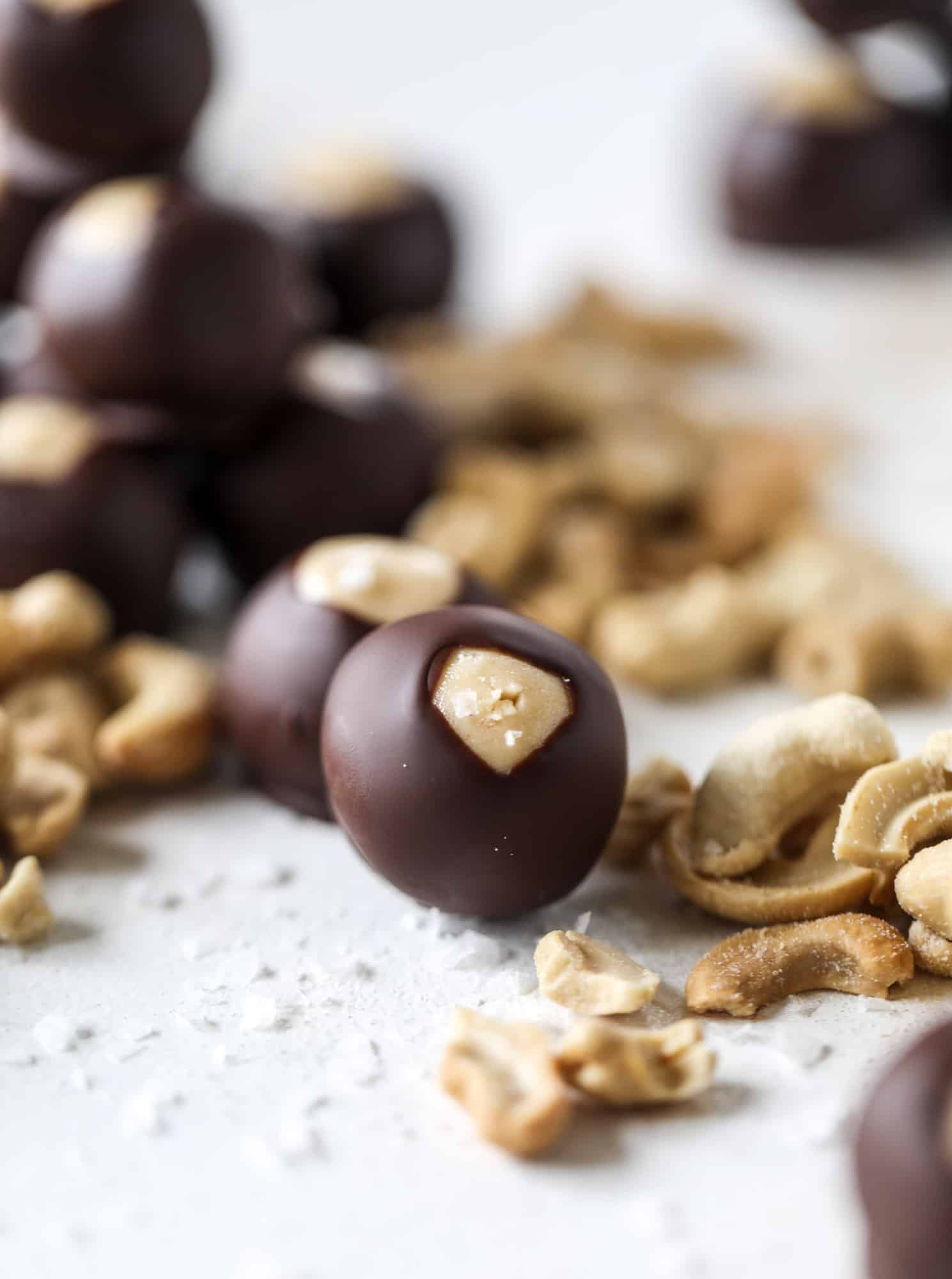 These cashew butter buckeyes are a fun and modern twist on the traditional buckeye recipe! Creamy cashew butter makes a delicious, rich dough and then it's coated in chocolate and sprinkled with sea salt. Delicious! I howsweeteats.com #cashewbutter #buckeyes