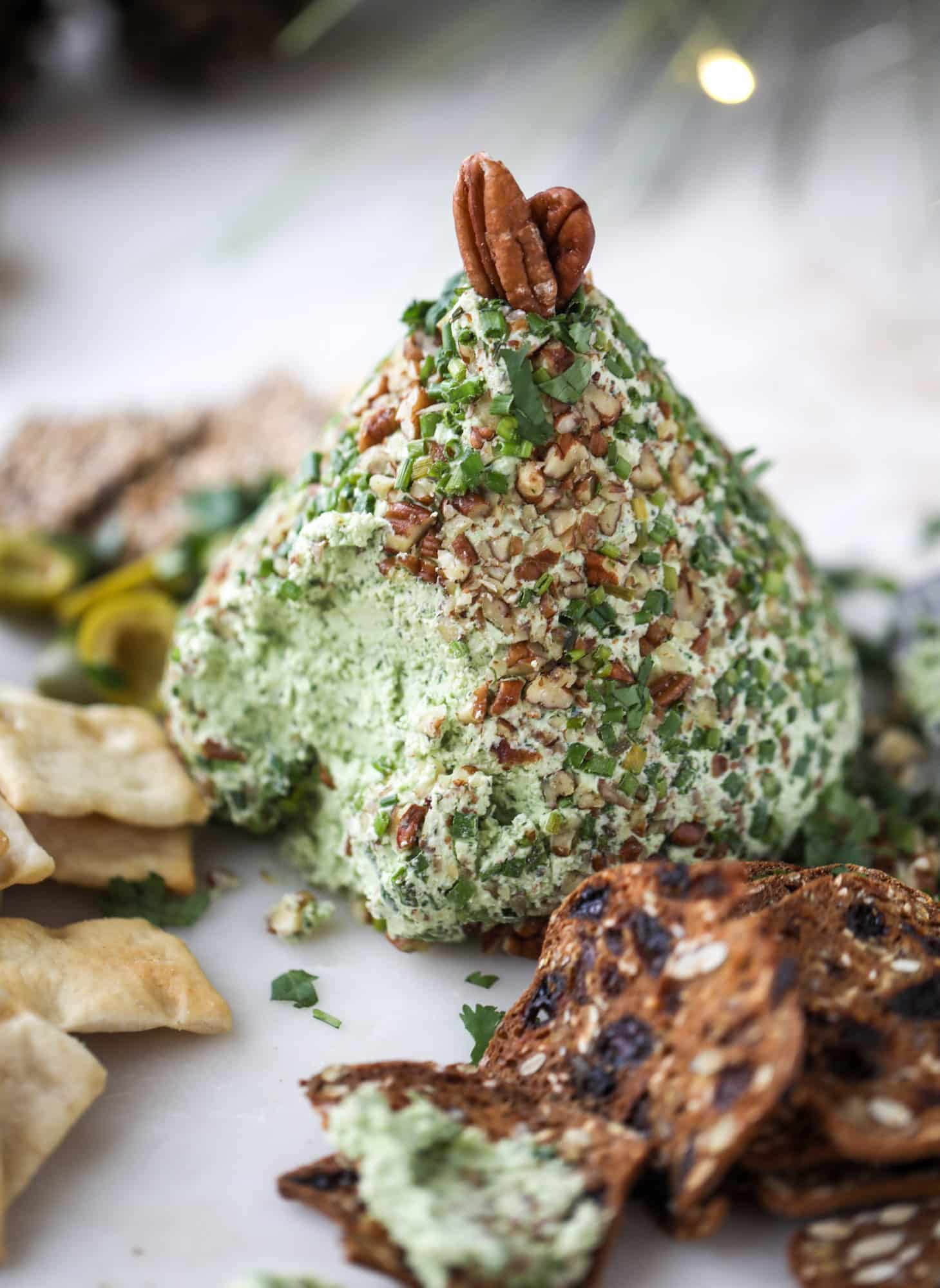 This green goddess cheese ball is the perfect party snack! You can make it ahead of time and shape it into a cute tree for a festive look. Serve it with crispy crackers and pita chips! I howsweeteats.com #greengoddess #cheeseball
