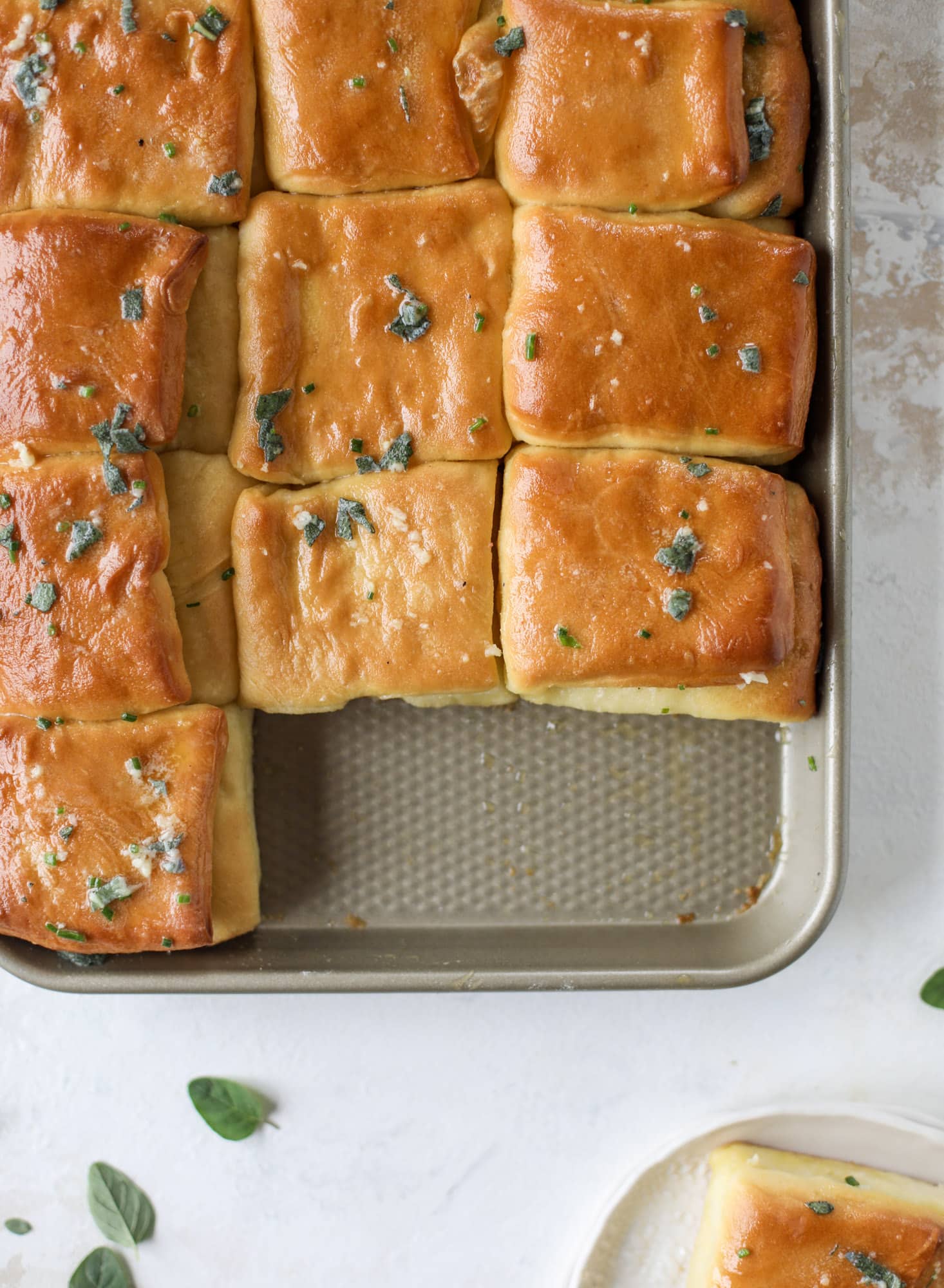 Garlic herb parker house rolls are full of incredibly buttery flavor! They are brushed with a garlic herb butter and are super fluffy, soft and tender. Perfect for Thanksgiving or the holidays and you can make the dough a bit ahead of time! I howsweeteats.com #parkerhouse #rolls