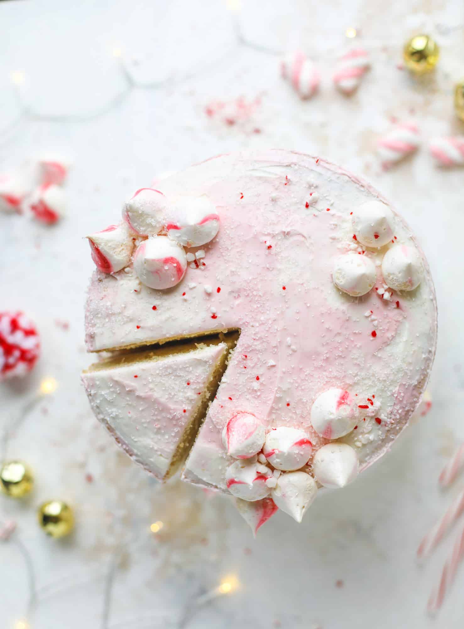 This pink peppermint cake is festive and delicious for the holidays! Layers of vanilla cake frosting with peppermint cream cheese frosting, covered in sparkly sugar and peppermint meringues. Couldn't be cuter! I #pinkpeppermint #cake