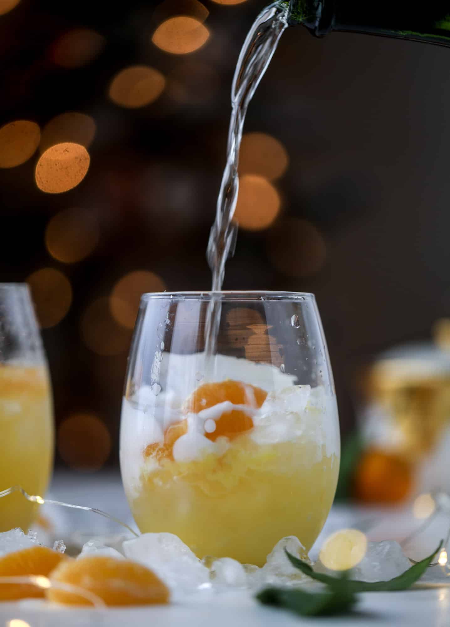 This satsuma cocktail is perfect for the holiday season and winter months when sweet satsumas are in season! This cocktail uses gin or vodka and is topped with champagne and garnished with a few satsuma wedges. Delicious! I howsweeteats.com #satsuma #cocktail