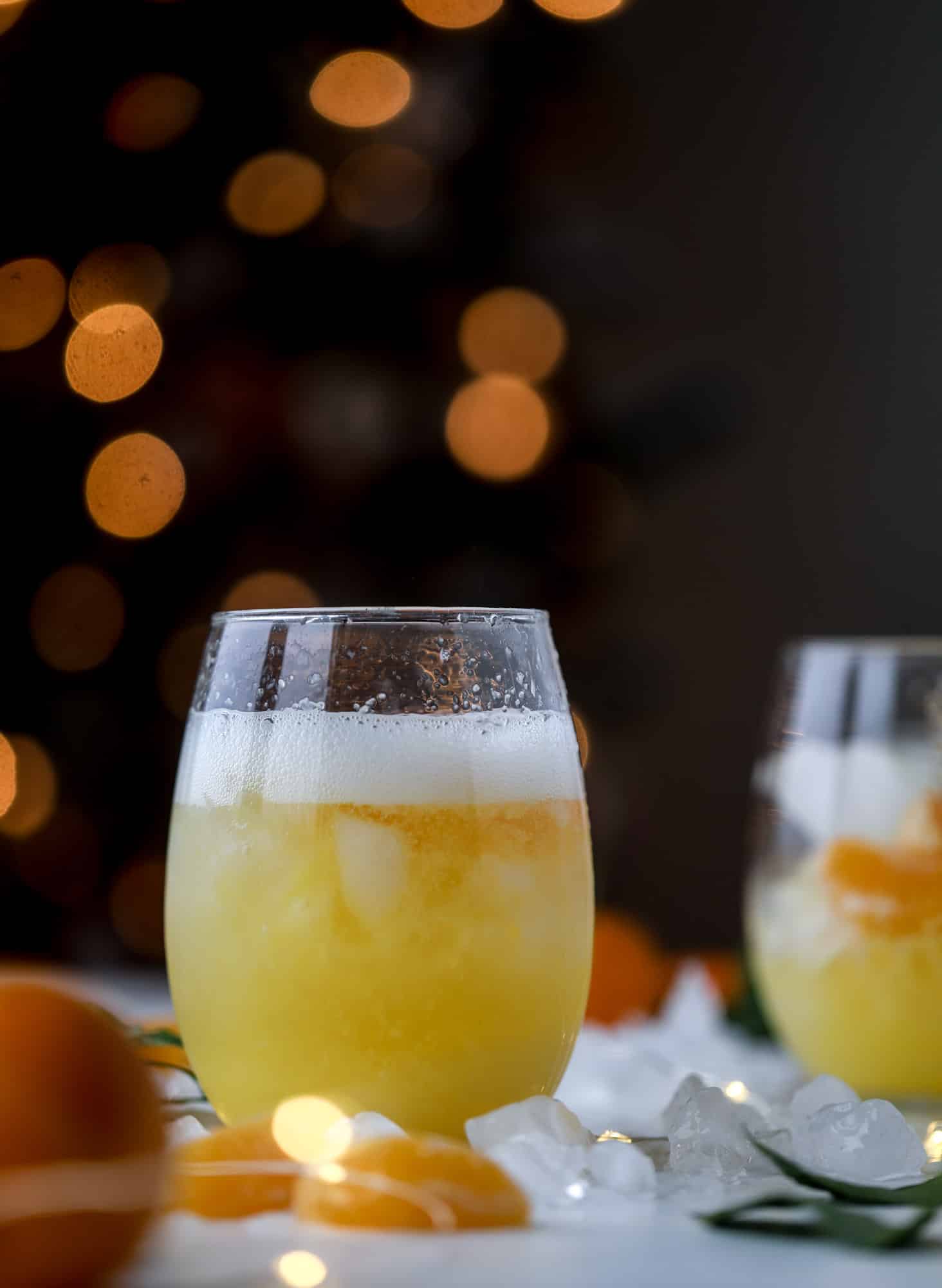 This satsuma cocktail is perfect for the holiday season and winter months when sweet satsumas are in season! This cocktail uses gin or vodka and is topped with champagne and garnished with a few satsuma wedges. Delicious! I howsweeteats.com #satsuma #cocktail