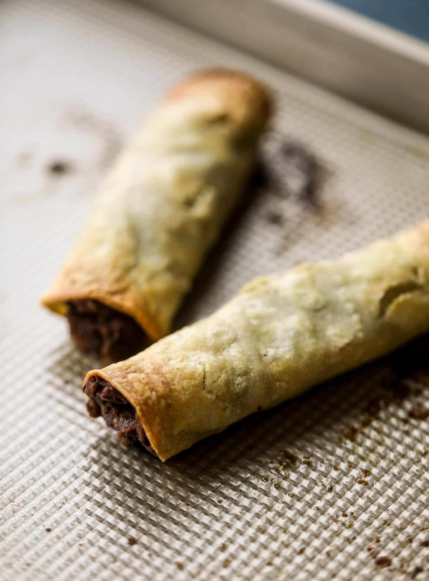 Saucy baked black bean taquitos have a crunchy outside and a creamy, flavorful inside. Served with a pico de gallo, they are an easy weeknight meal! I howsweeteats.com #baked #taquitos