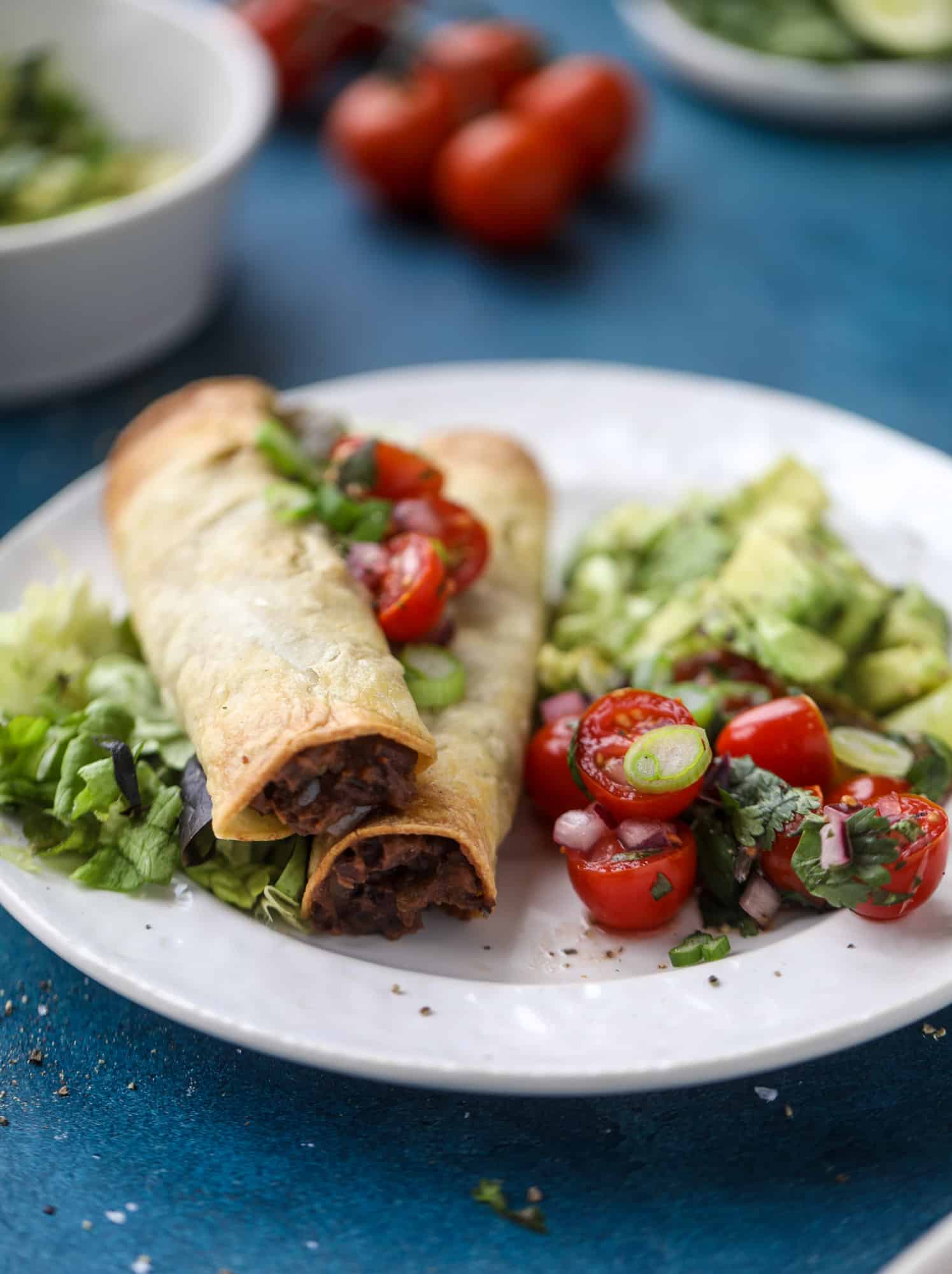 Saucy baked black bean taquitos have a crunchy outside and a creamy, flavorful inside. Served with a pico de gallo, they are an easy weeknight meal! I howsweeteats.com #baked #taquitos