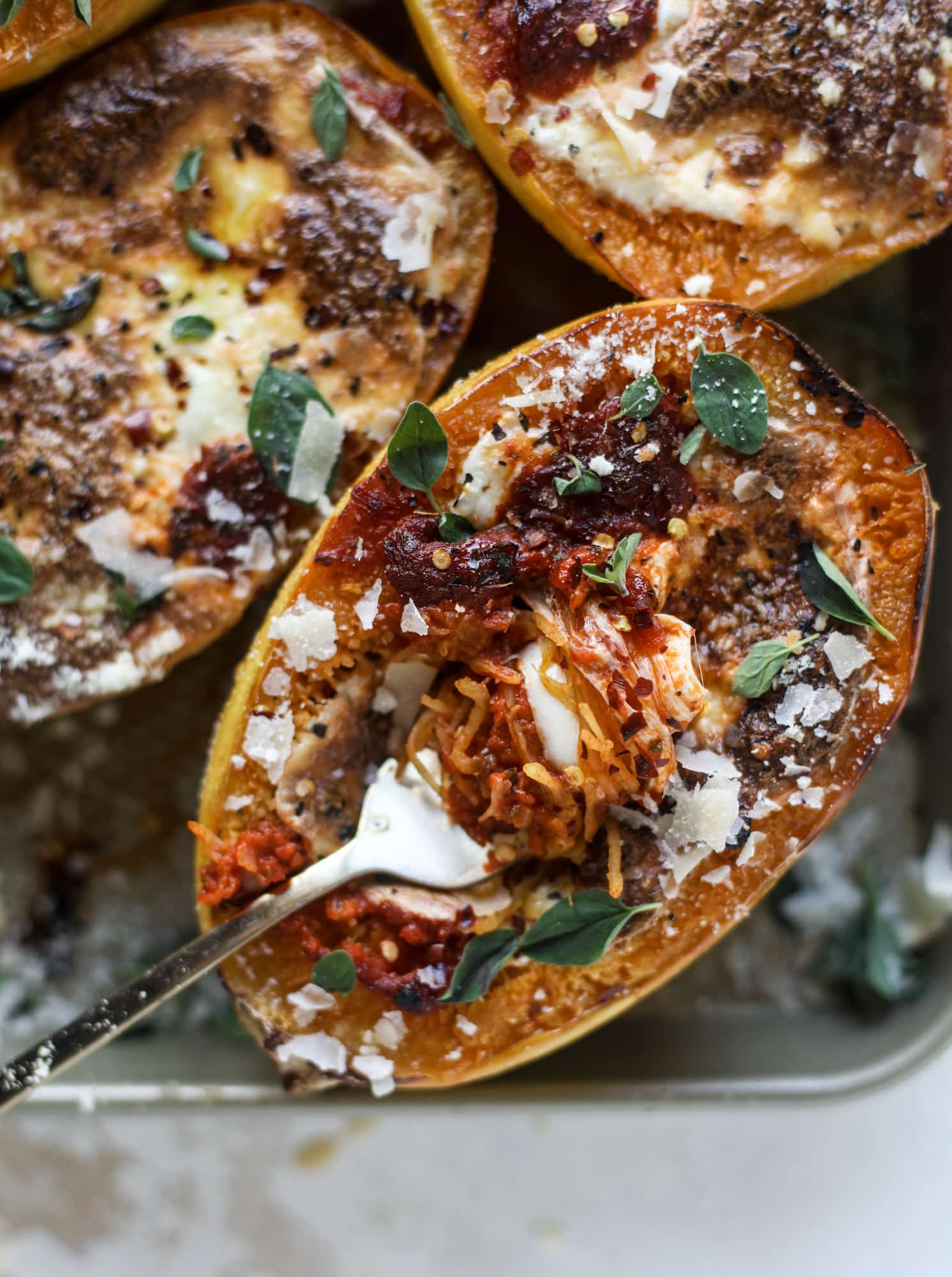 Spaghetti squash parmesan is a delicious weeknight meal! Topped with marinara or bolognese, melty cheese and fresh herbs, it's easy and delicious! I howsweeteats.com #spaghettisquash #parmesan
