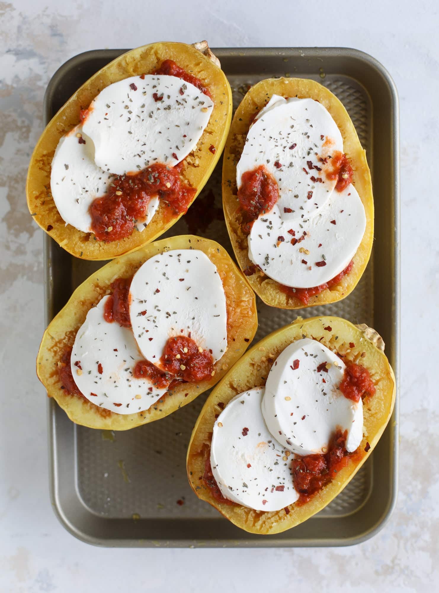 Spaghetti squash parmesan is a delicious weeknight meal! Topped with marinara or bolognese, melty cheese and fresh herbs, it's easy and delicious! I howsweeteats.com #spaghettisquash #parmesan