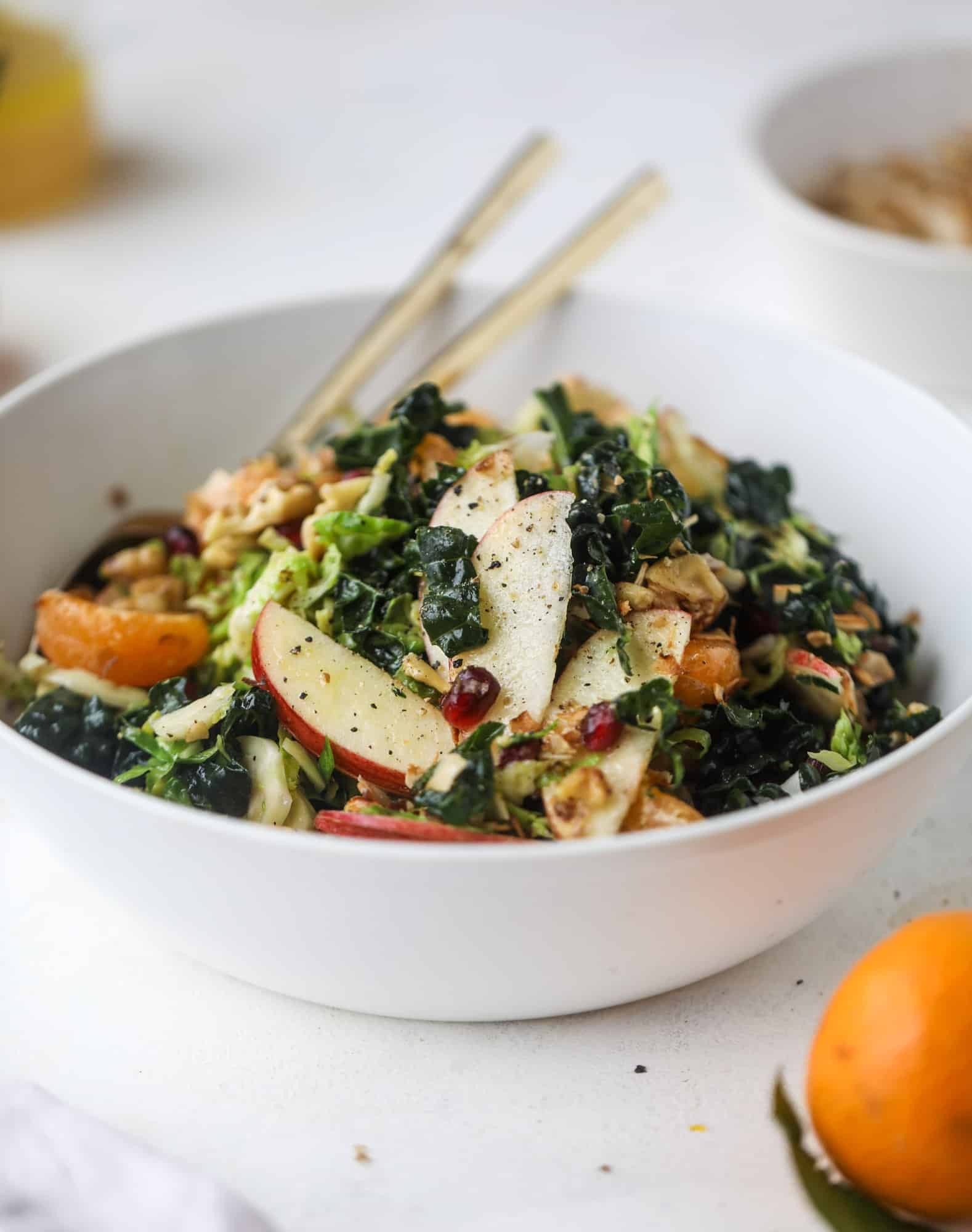 This winter crunch salad is loaded with tons of delicious, crunchy seasonal ingredients. A base of brussels sprouts and kale is topped with sliced apples, satsuma wedges, pomegranate arils, toasted walnuts and savory flaked coconut crunch. Delish! I howsweeteats.com #winter #salad