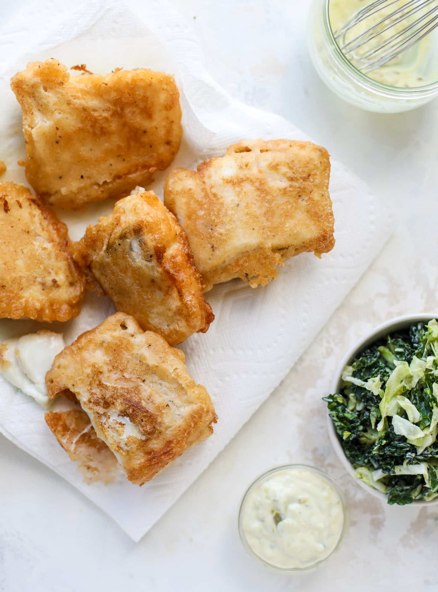 A light and crispy fish sandwich made with a simple beer batter and topped with a hearty, creamy kale cole slaw. Loaded with flavor! I howsweeteats.com #crispyfish #sandwich