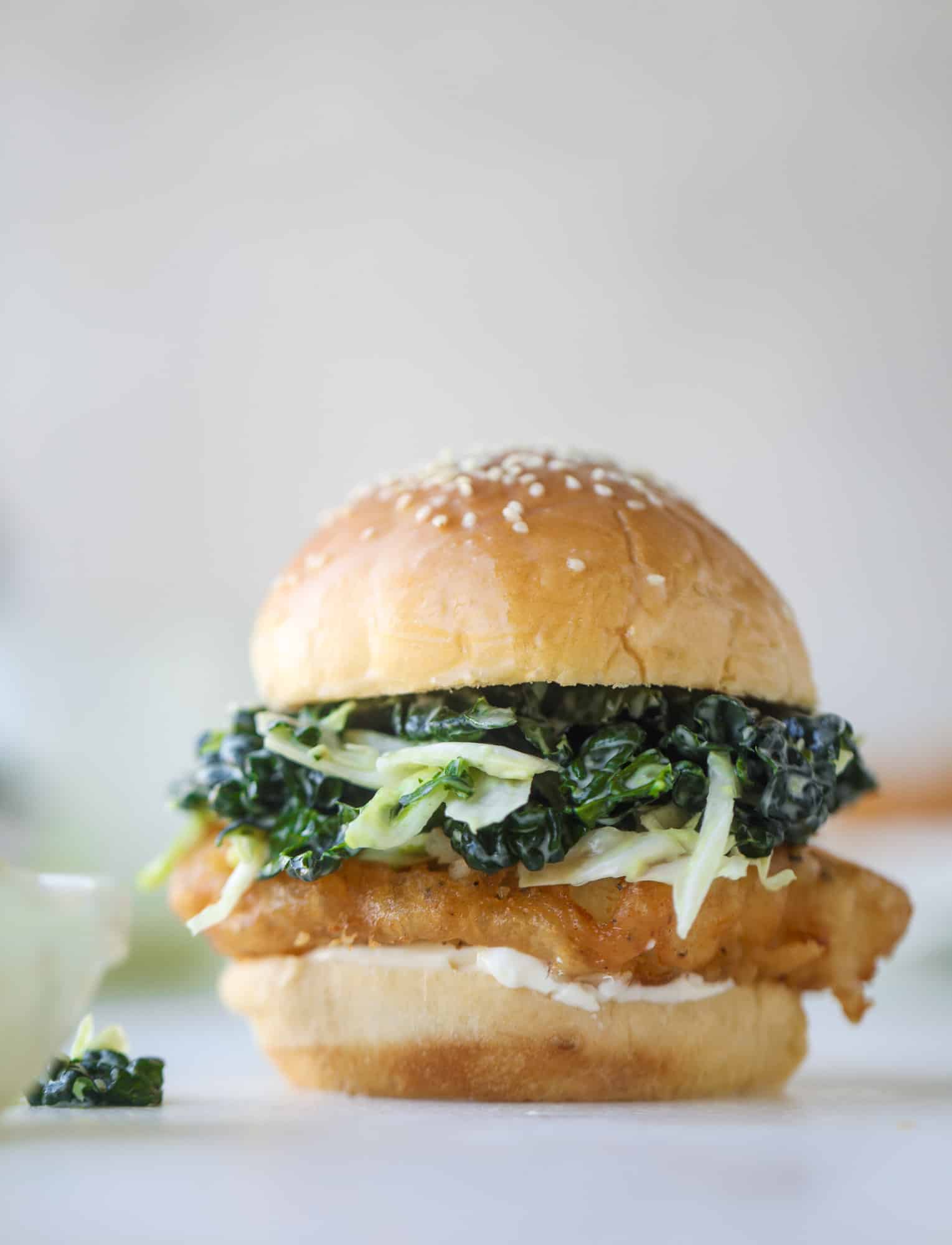 A light and crispy fish sandwich made with a simple beer batter and topped with a hearty, creamy kale cole slaw. Loaded with flavor! I howsweeteats.com #crispyfish #sandwich