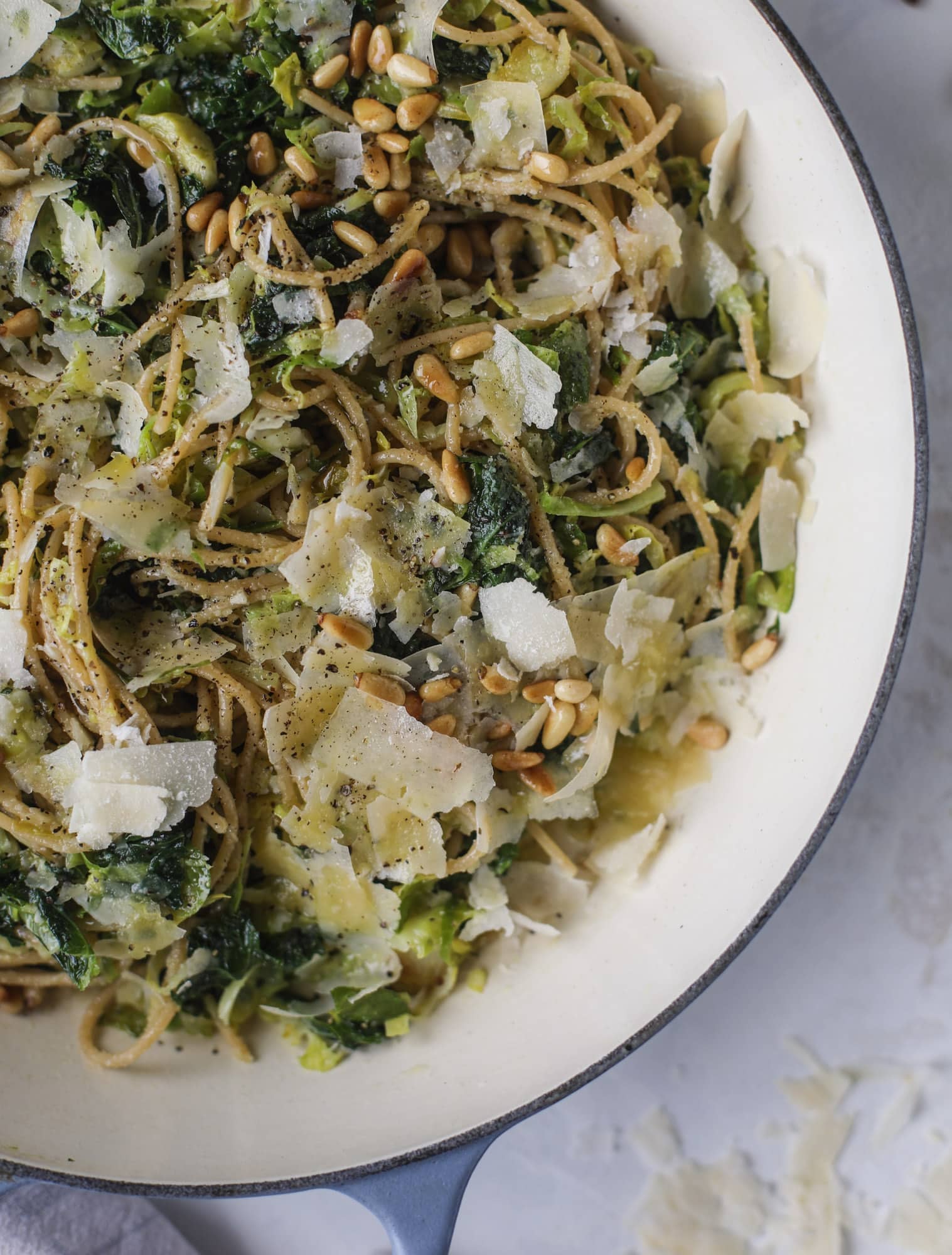 This brussels spaghetti with kale, parmesan and pine nuts is a super flavorful, quick and easy weeknight meal. You can add in a protein if you wish! I howsweeteats.com #brussels #spaghetti