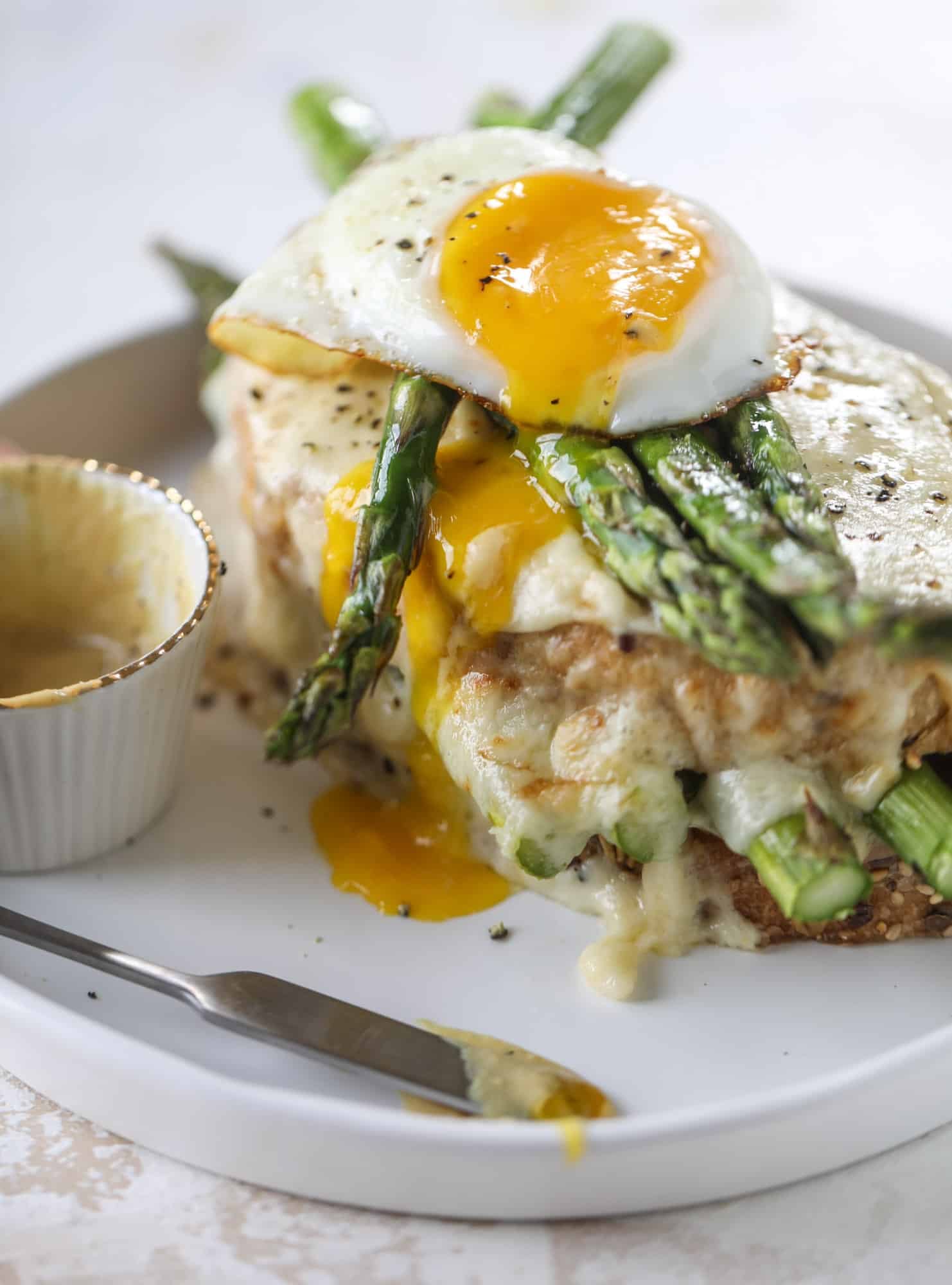 This roasted asparagus croque madame is made with thinly-sliced prosciutto and a fontina cheese sauce. Lots of dijon and an egg on top! I howsweeteats.com #croquemadame #asparagus