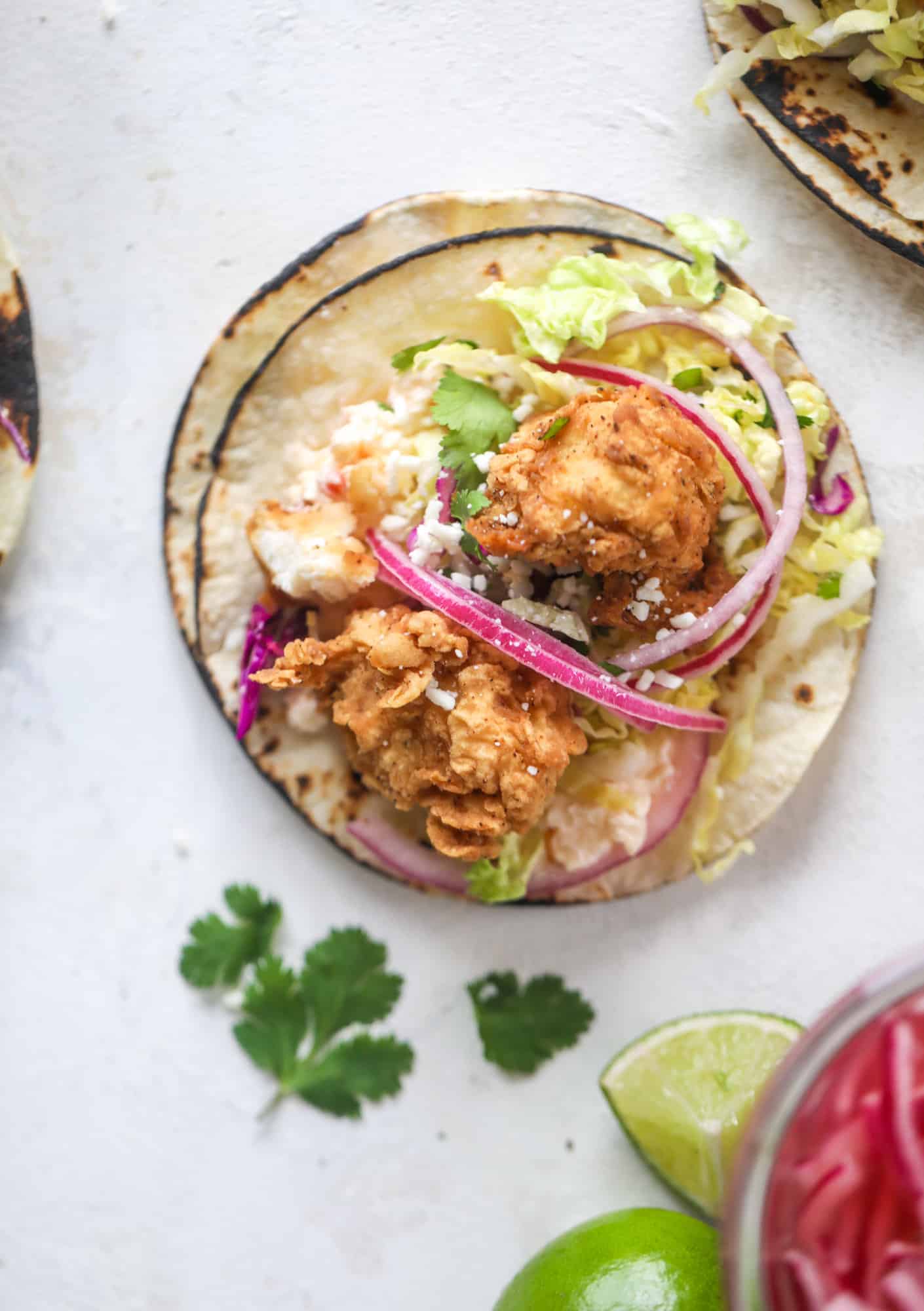 Taking crispy chicken tacos to the next level by wrapping them in a warm tortilla with gouda pimento cheese, lime cabbage and pickled onions!