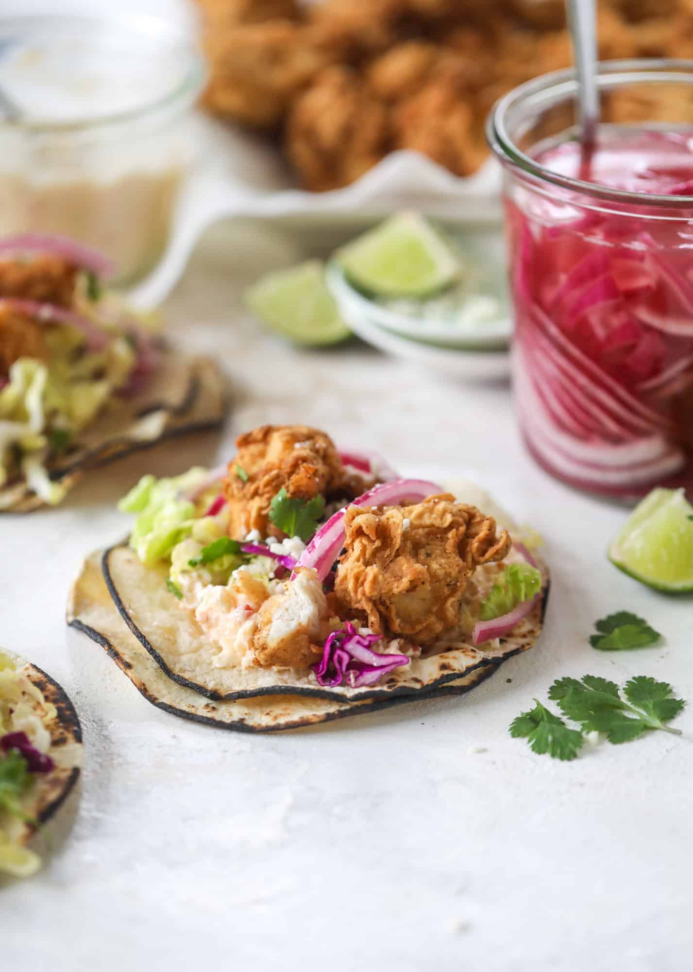 Taking crispy chicken tacos to the next level by wrapping them in a warm tortilla with gouda pimento cheese, lime cabbage and pickled onions!