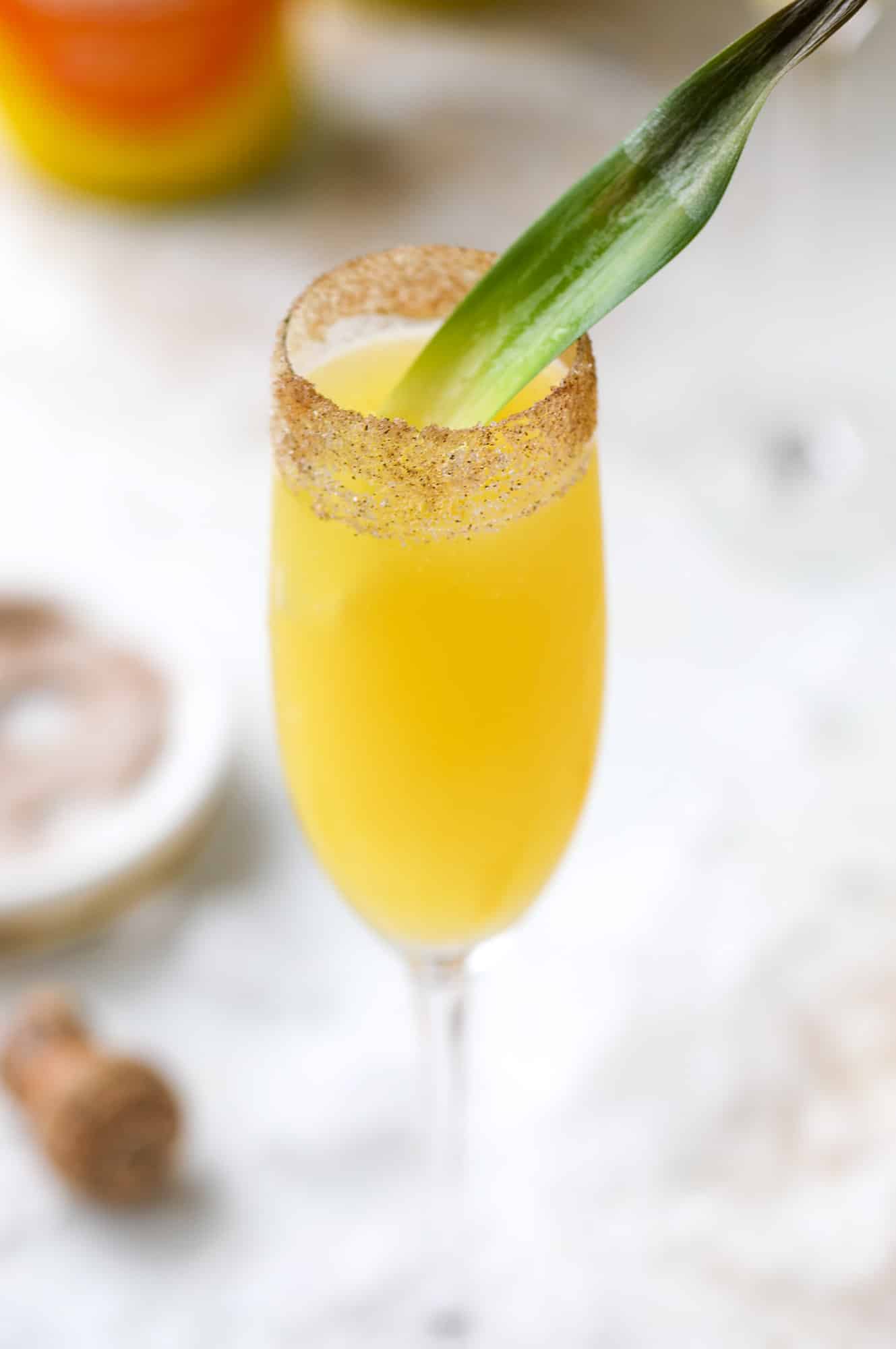 The hummingbird mimosa is a spin on the classic hummingbird cake: pineapple juice, orange juice, champagne and a cinnamon sugar rim! I howsweeteats.com #hummingbird #mimosa