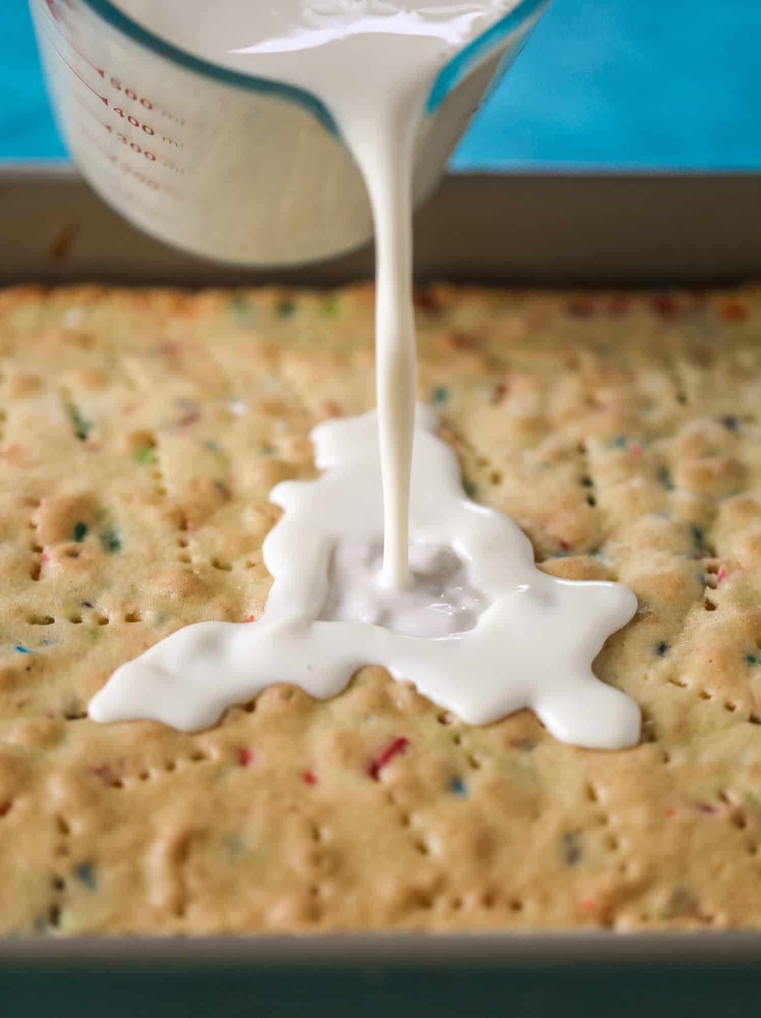 pouring the milks on tres leches cake