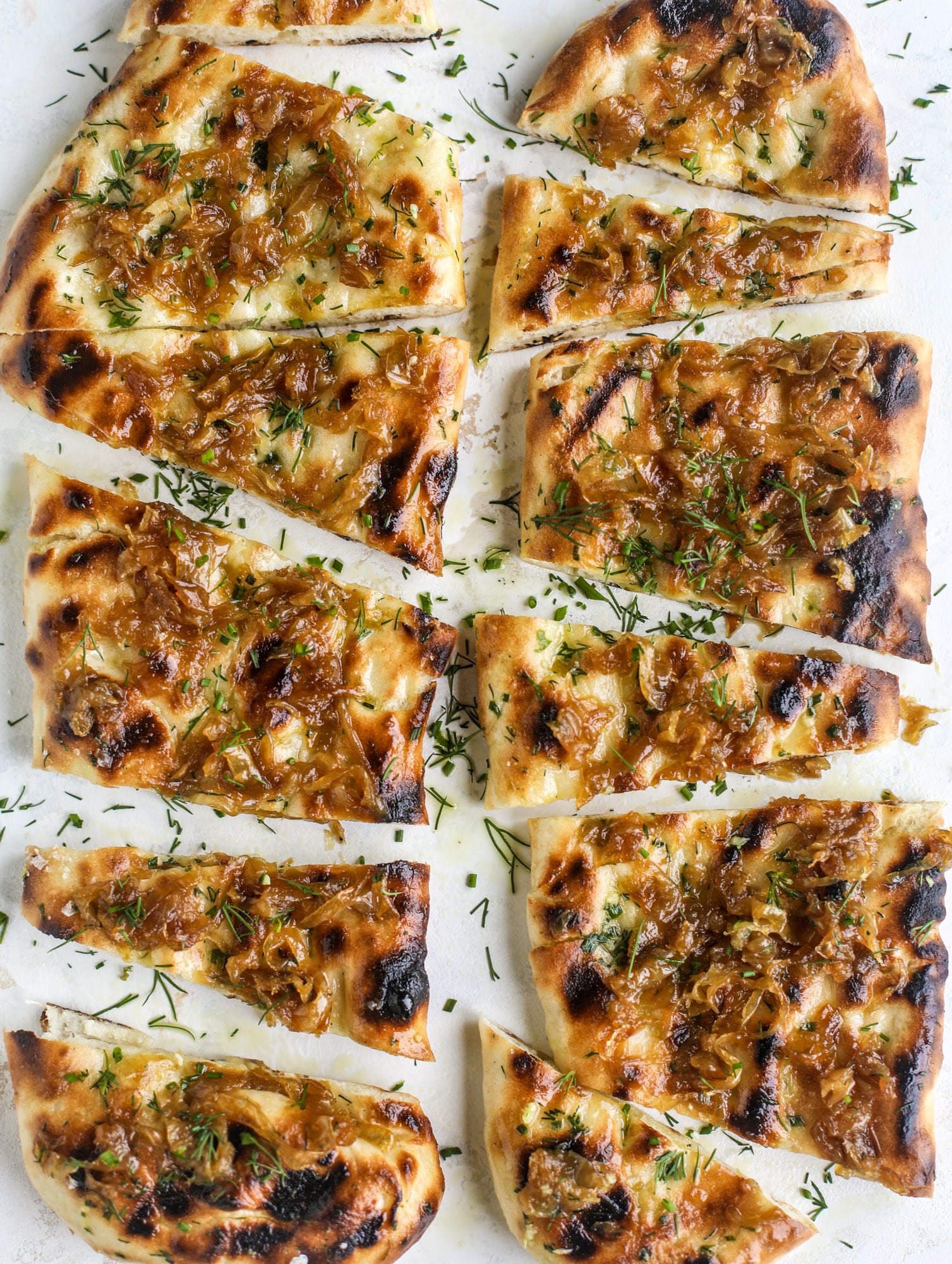 Grilled focaccia bread is such a treat! Topped with puddles of garlic butter, fresh chopped herbs and golden, caramelized onions, it's a slice of heaven.