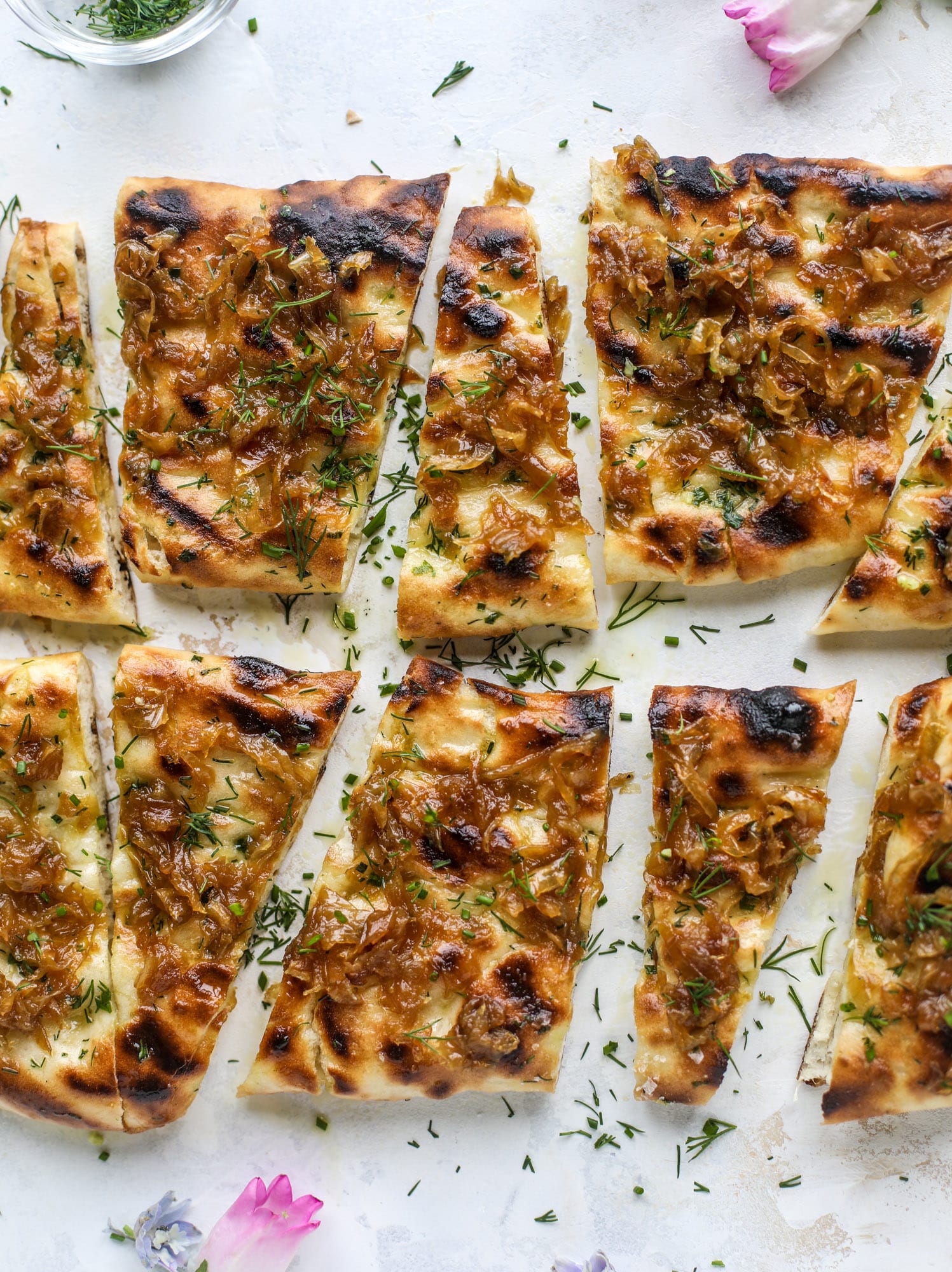 Grilled focaccia bread is such a treat! Topped with puddles of garlic butter, fresh chopped herbs and golden, caramelized onions, it's a slice of heaven.