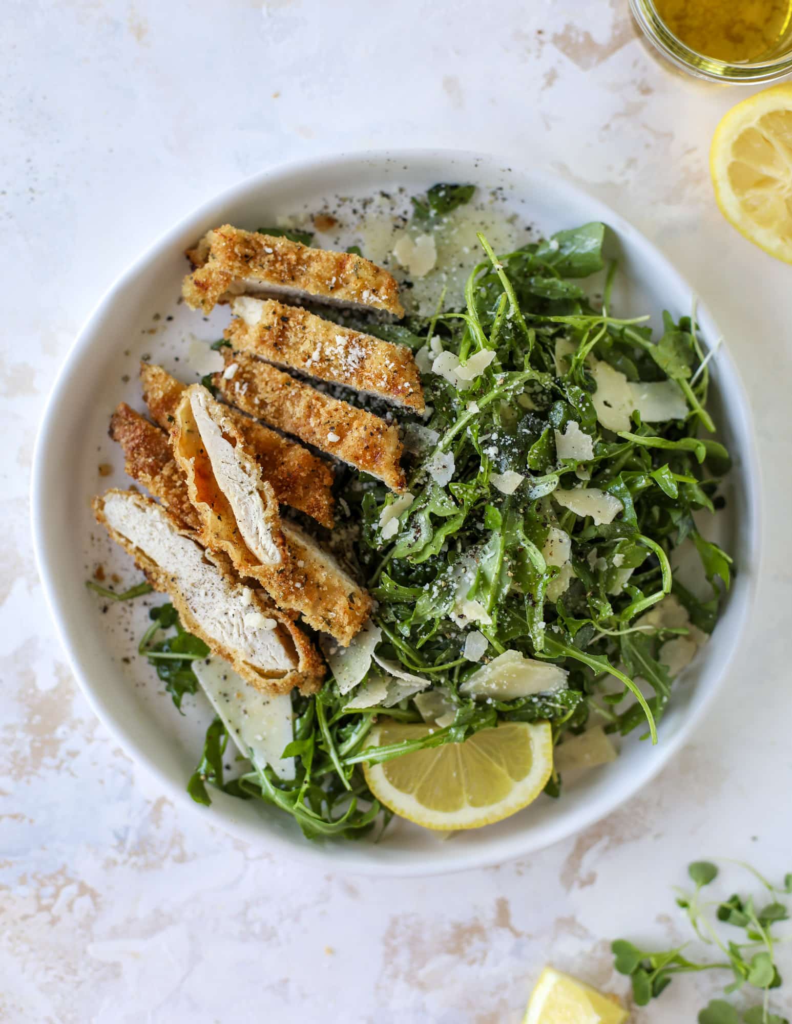 Crispy baked parmesan chicken is so super easy and delicious! It's an amazing weeknight meal served with a lemon arugula salad. Delish!