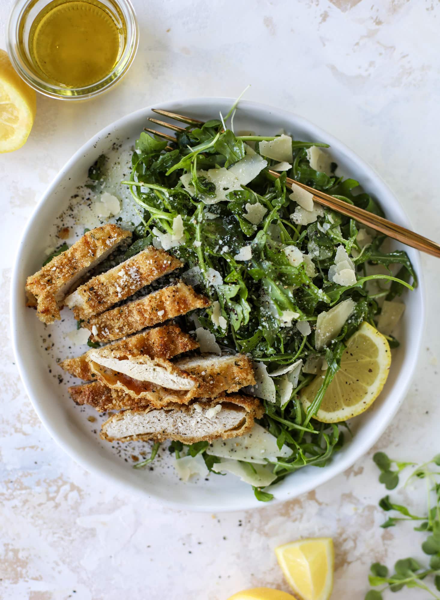 Crispy baked parmesan chicken is so super easy and delicious! It's an amazing weeknight meal served with a lemon arugula salad. Delish!