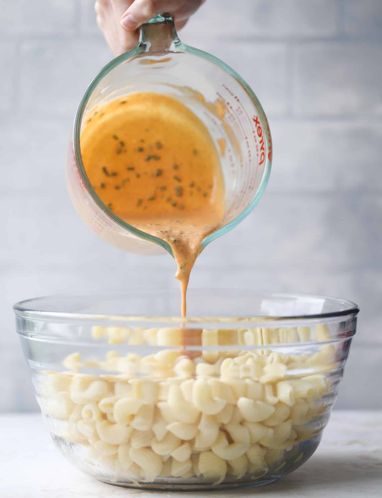 pouring dressing on pasta salad