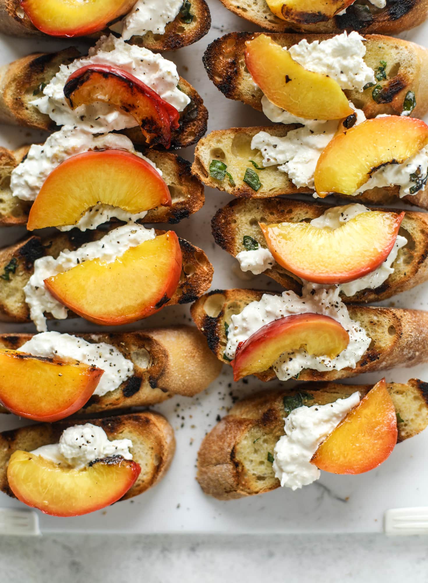 This peach burrata crostini is the best summer appetizer! it starts with grilled basil butter toasts that are topped with burrata, peach and pancetta!