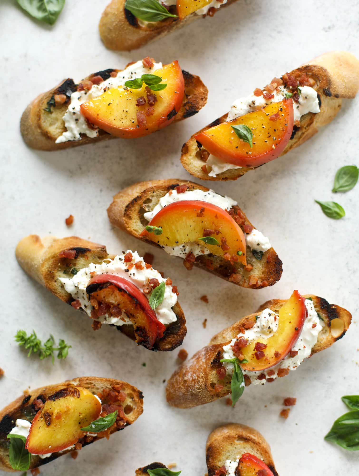 This peach burrata crostini is the best summer appetizer! it starts with grilled basil butter toasts that are topped with burrata, peach and pancetta!
