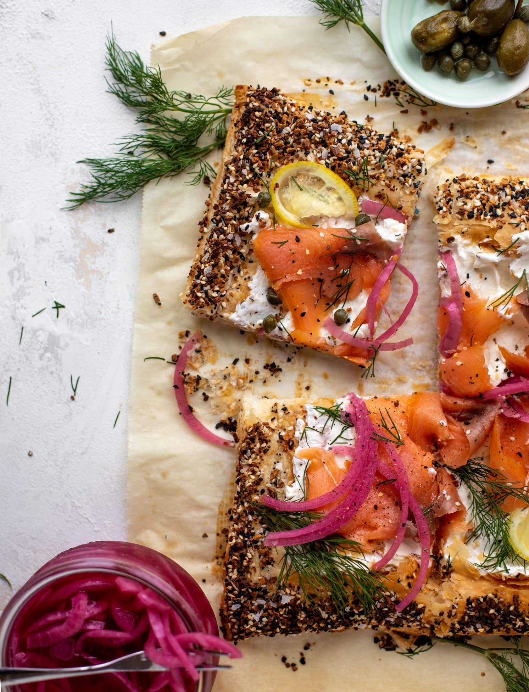 This everything smoked salmon tart is perfect for brunch! Puff pastry sprinkled with everything seasoning, slathered in cream cheese and topped with salmon.