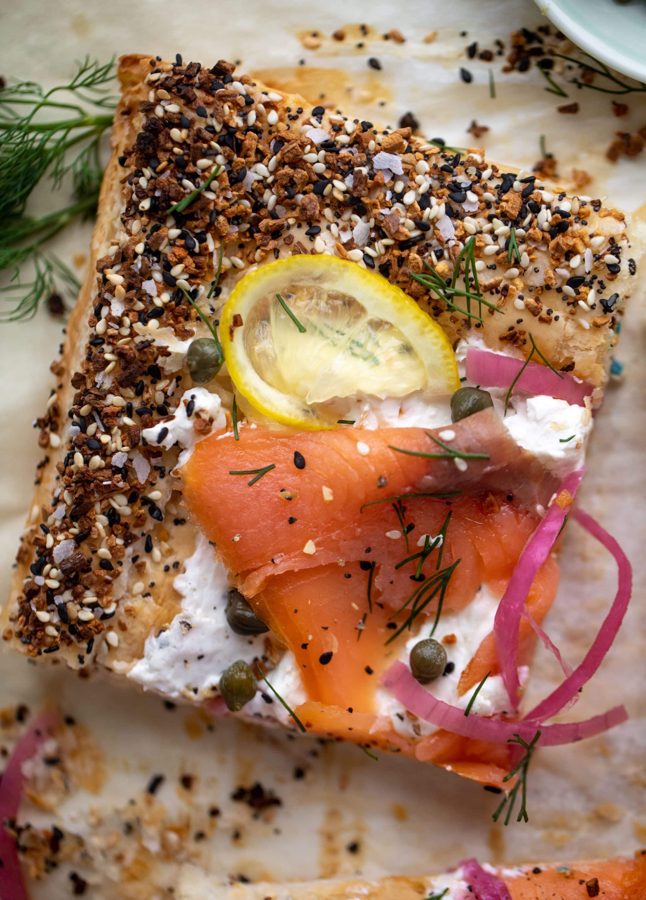 This everything smoked salmon tart is perfect for brunch! Puff pastry sprinkled with everything seasoning, slathered in cream cheese and topped with salmon.