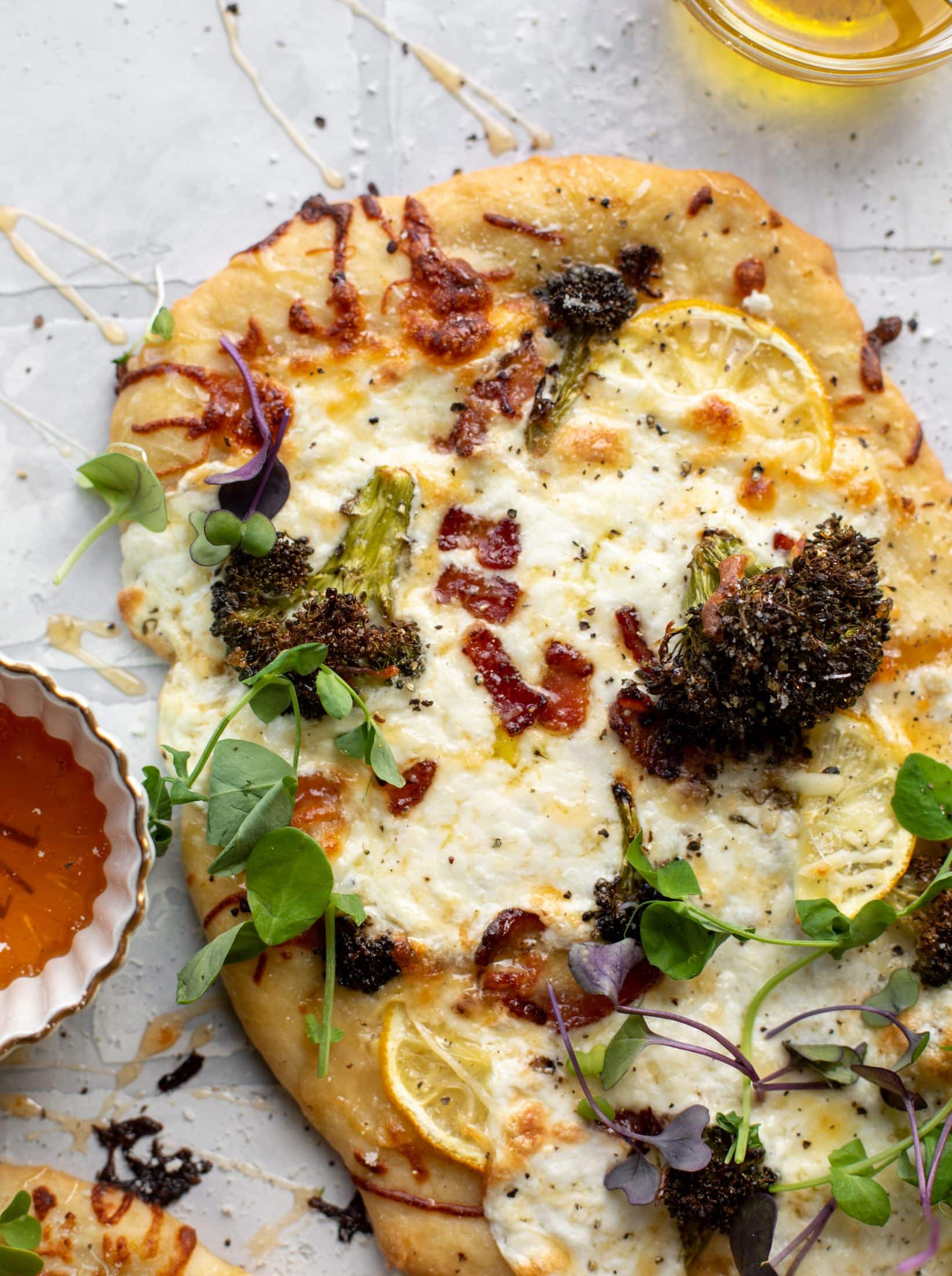 This cheesy lemon flatbread pizza is covered with burrata cheese, parmesan, roasted vegetables and hot honey. It's a flavor dream!