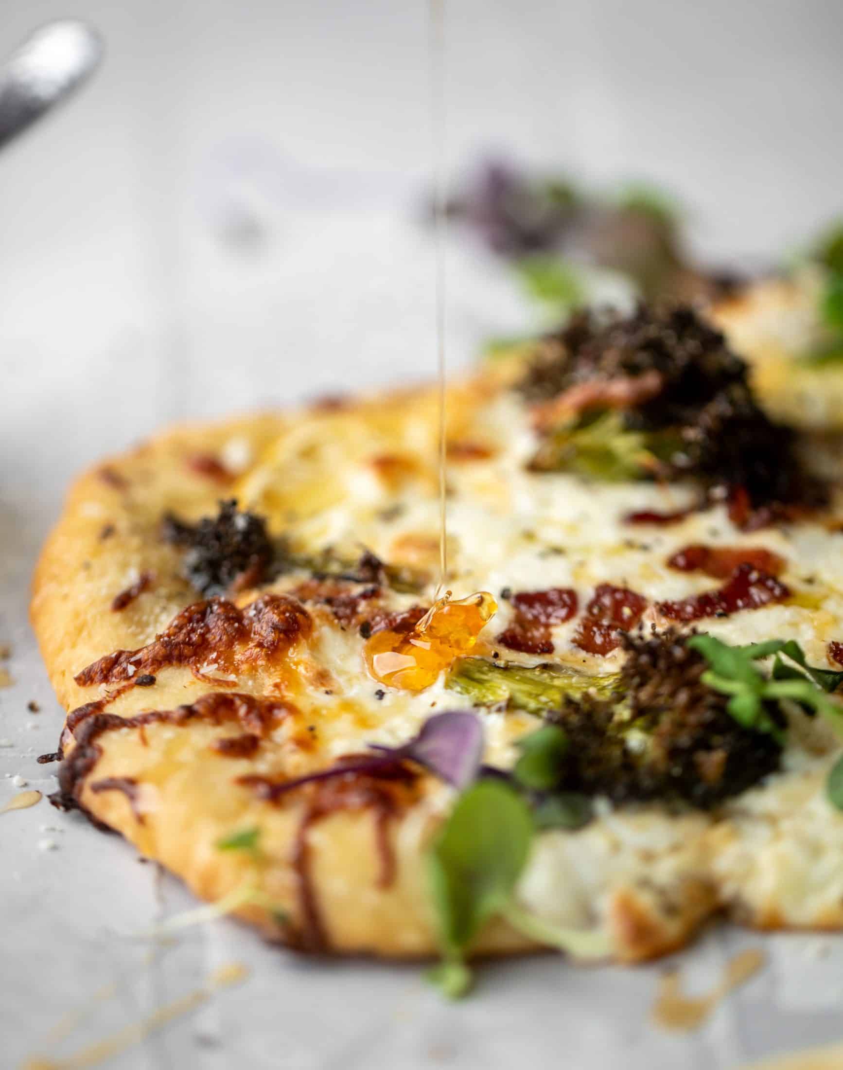 This cheesy lemon flatbread pizza is covered with burrata cheese, parmesan, roasted vegetables and hot honey. It's a flavor dream!