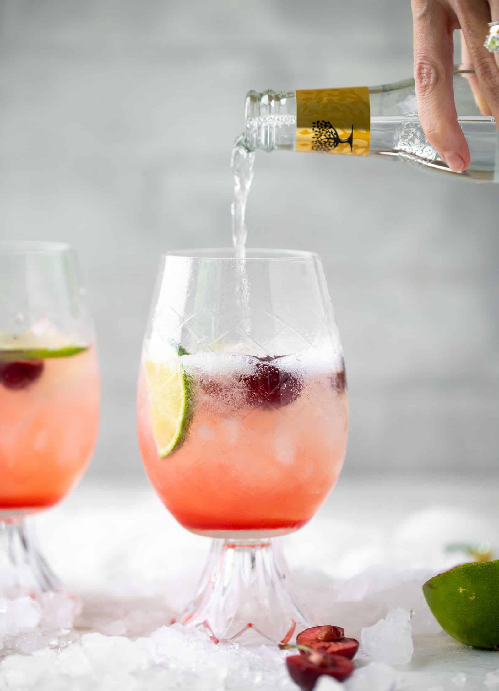 pouring tonic into cherry lime gin and tonic