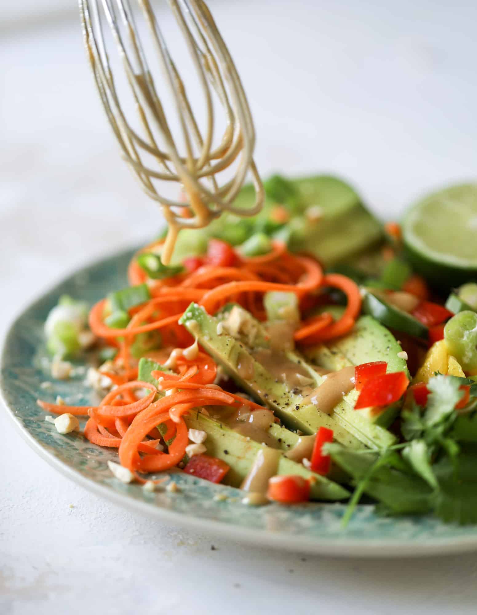 This thai avocado salad is loaded with mango, red pepper, carrots, green onions and drizzled with a peanut butter vinaigrette. It's an amazing side salad or a fabulous dinner salad - add on chickpeas or shrimp or chicken if you wish! I howsweeteats.com #thai #avocado #salad #peanutbutter #mango #lime