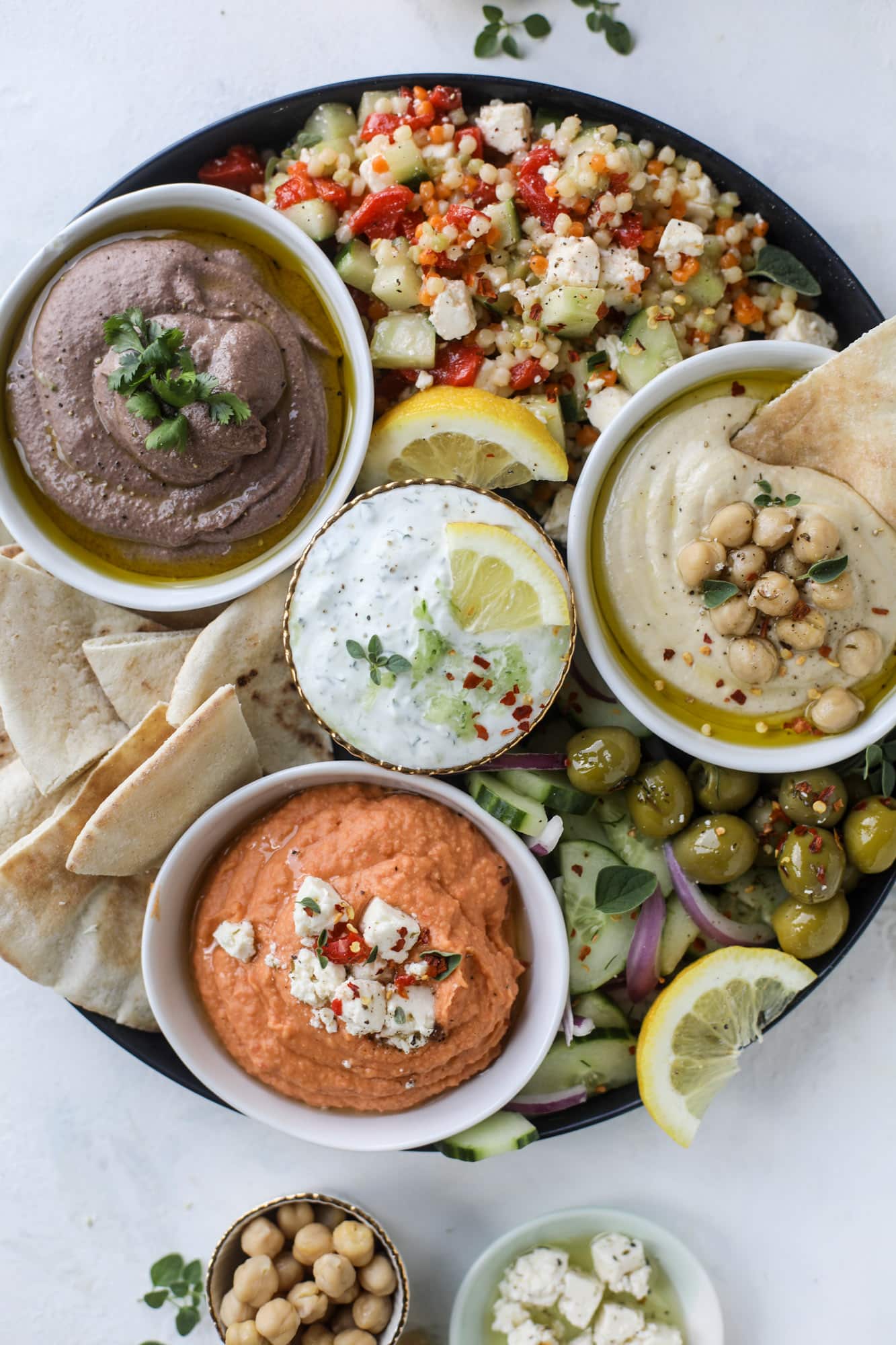 Here you can find out how to make the perfect hummus platter! This trio includes caramelized onion hummus, smoky black bean hummus and roasted red pepper white bean hummus, along with a couscous salad and quick tzatziki! I howsweeteats.com #hummus #platter #appetizer #snack #chickpeas #healthy #blackbeans #yogurt #tzatziki