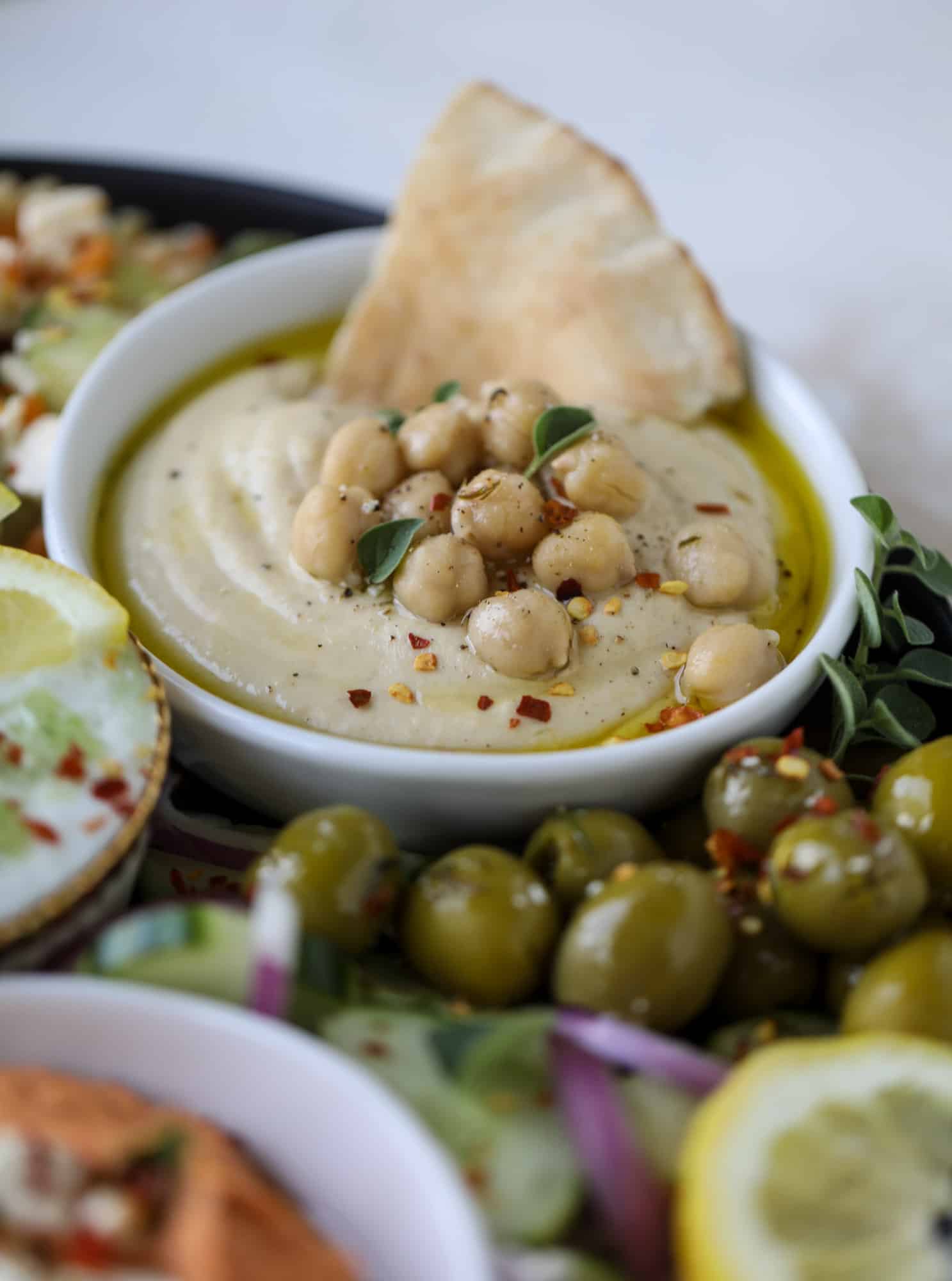 Here you can find out how to make the perfect hummus platter! This trio includes caramelized onion hummus, smoky black bean hummus and roasted red pepper white bean hummus, along with a couscous salad and quick tzatziki! I howsweeteats.com #hummus #platter #appetizer #snack #chickpeas #healthy #blackbeans #yogurt #tzatziki