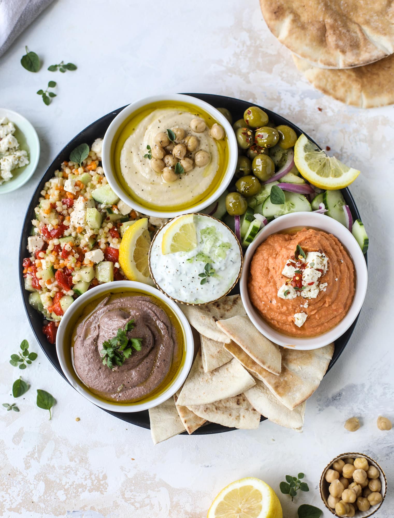 Here you can find out how to make the perfect hummus platter! This trio includes caramelized onion hummus, smoky black bean hummus and roasted red pepper white bean hummus, along with a couscous salad and quick tzatziki! I howsweeteats.com #hummus #platter #appetizer #snack #chickpeas #healthy #blackbeans #yogurt #tzatziki