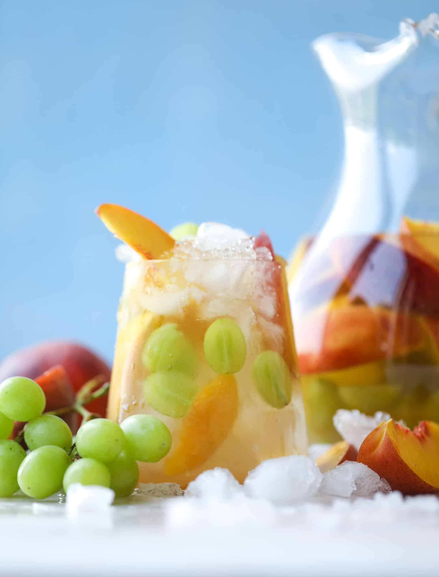 This pinot grigio sangria is absolutely perfect for summer, complete with peach nectar, fresh and frozen peach slices, brandy and bubbles! Frozen green grapes add some chill without watering down the drink. It's perfect! I howsweeteats.com #pinot #grigio #peach #sangria #cocktails #punch #summer #wine