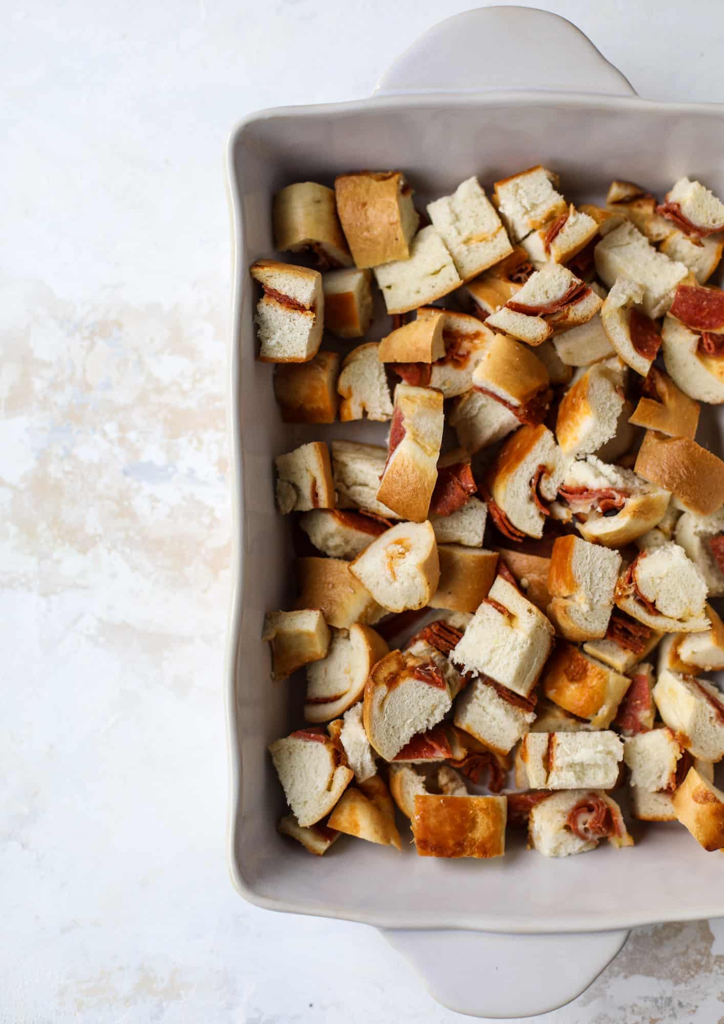 This breakfast strata is super special because the base is built on pepperoni rolls! This make ahead casserole is perfect for holiday brunches or parties and tastes like a supreme pizza. It's so easy to throw together too! I howsweeteats.com #breakfast #strata