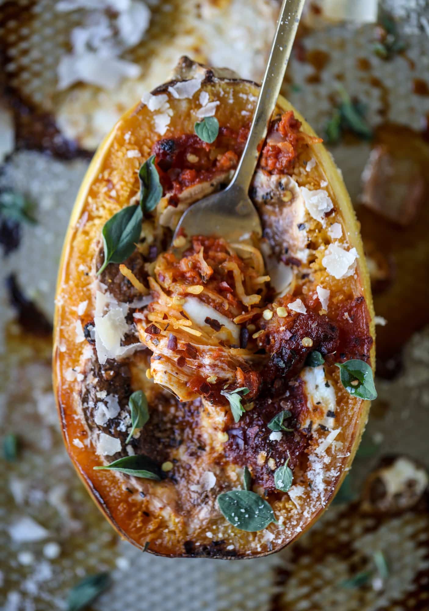 Spaghetti squash parmesan is a delicious weeknight meal! Topped with marinara or bolognese, melty cheese and fresh herbs, it's easy and delicious! I howsweeteats.com #spaghettisquash #parmesan