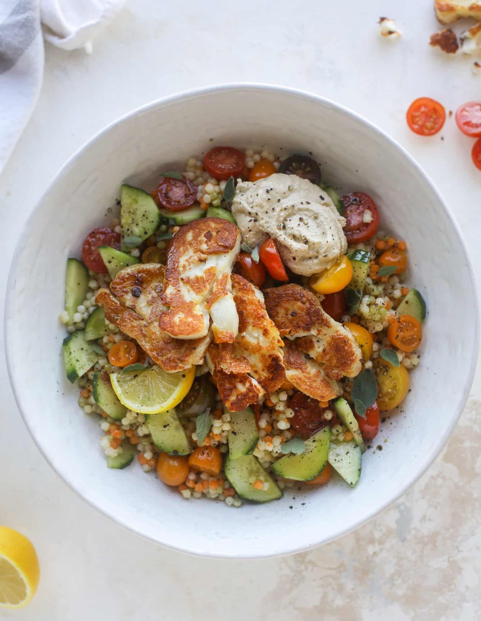 I am obsessed with these haulloumi hummus bowls for lunch or dinner. Couscous, veggies, crispy halloumi cheese and hummus with lots of lemon. Yum! I howsweeteats.com #halloumi #hummus